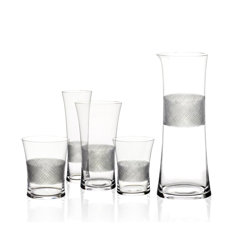 The Drinking Set No. 282 - Diamond Cut by Lobmeyr includes a tall carafe and four glasses, each embellished with a textured silver band in Ted Muehlings style, arranged from shortest to tallest against a plain white background.