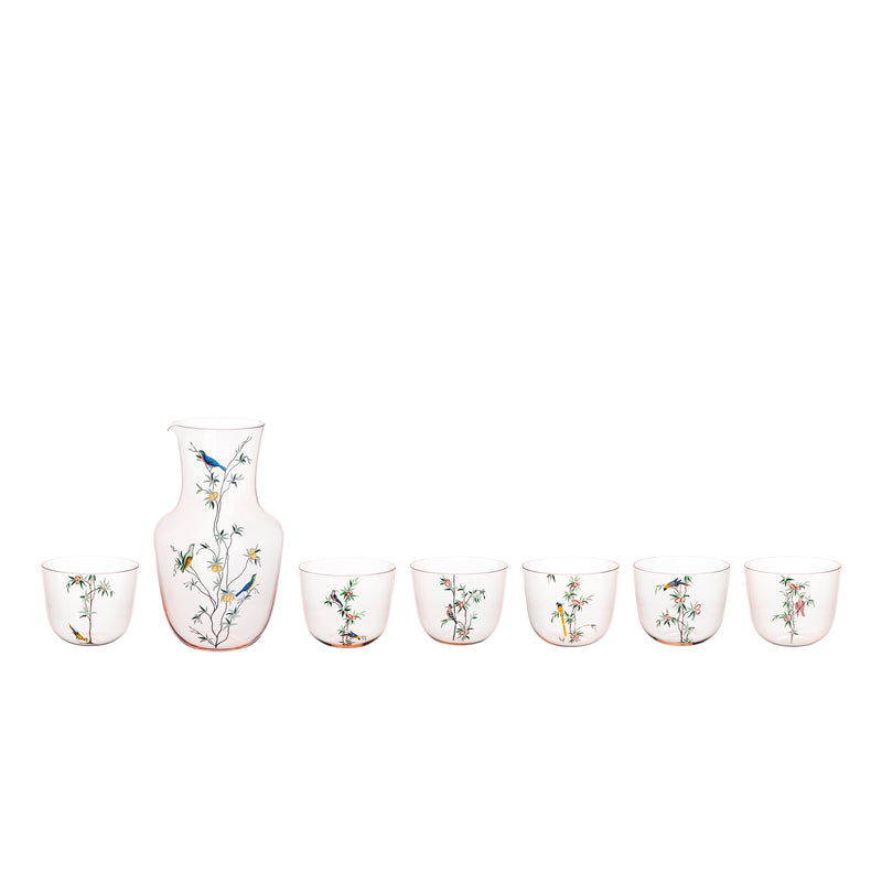 The Lobmeyr Alpha Pitcher - Garden of Paradise set includes six clear glass cups and a taller, wider pitcher, each elegantly decorated with bird and branch motifs. The rosalin water tumbler set is beautifully lined up against a plain white background.