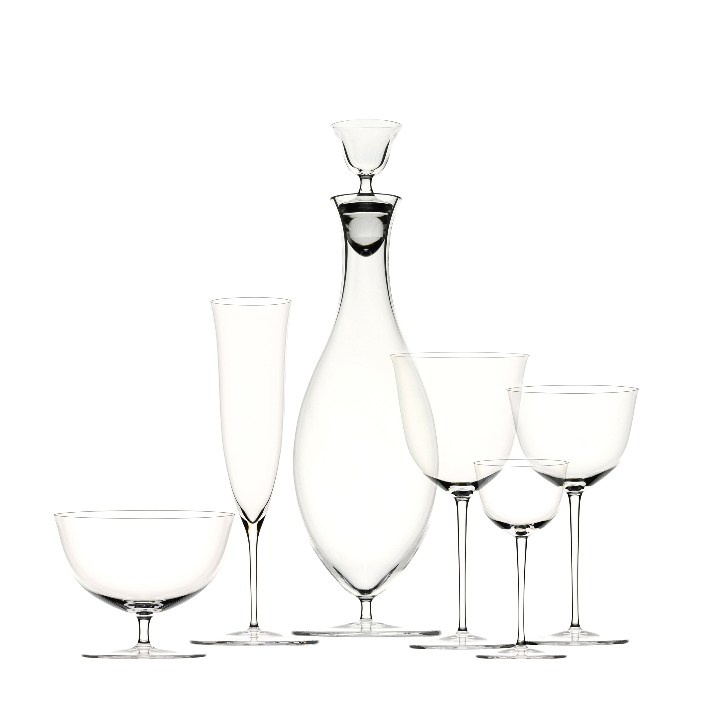 The Drinking Set No. 238 - Patrician by Lobmeyr features a tall, slender decanter with a stopper, surrounded by wine glasses and a champagne flute, set against a plain white background. This clear, mouth-blown crystal glassware echoes Josef Hoffmanns elegant design ethos for the Wiener Werkstätte.