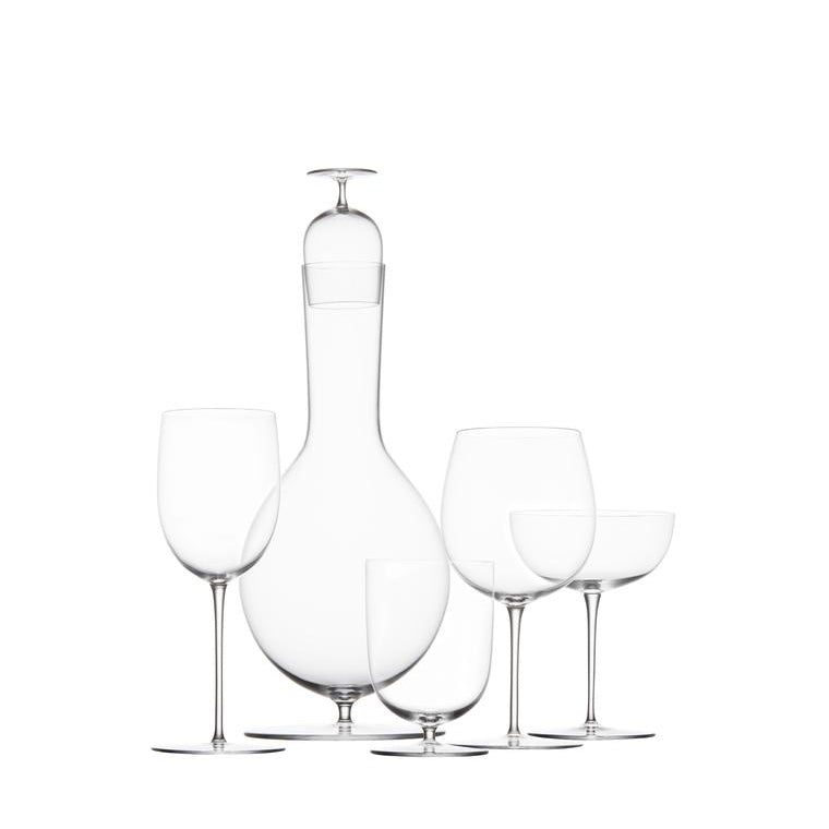 The Drinking Set No. 280 - Wiener Gemischter Satz by Lobmeyr includes a tall, elegant wine decanter, two exquisite crystal wine glasses, a champagne coupe, and a smaller glass, all mouth-blown and set against a pristine white background.