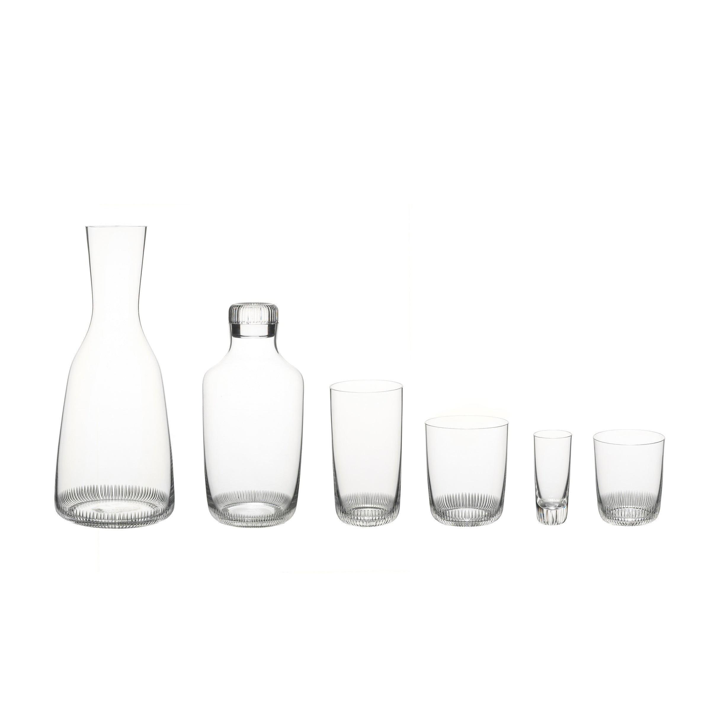 The Drinking Set No. 281 - Grip by Lobmeyr features six mouth-blown crystal pieces on a white background, including a carafe, bottle with stopper, two medium glasses, a smaller glass, and a shot glass. Each piece is adorned with Marco Dessis signature subtle vertical ribbing at the base.