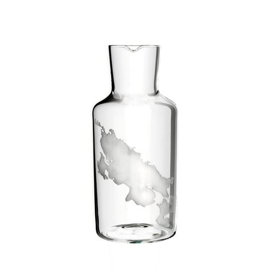 The Fortune Series by Lobmeyr is a mouth-blown crystal bottle with a narrow neck and small spout, adorned with a white cloud-like pattern. Its transparent design adds elegance, making it an ideal water carafe for sophisticated settings.