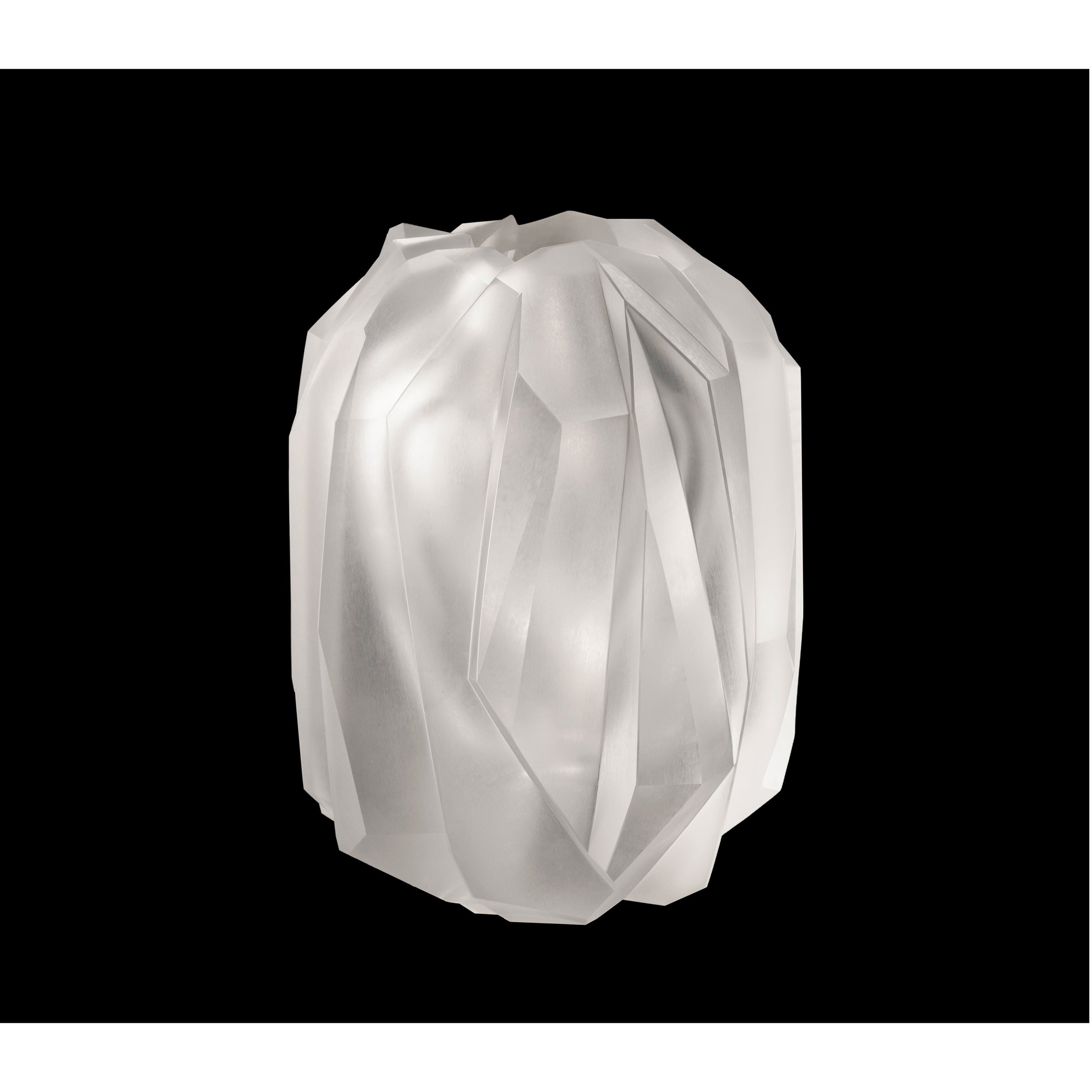 The Lobmeyr Gletscher Vase, a white faceted sphere, exudes a soft glow against a black background. Its hand-cut crystal surfaces are angular and geometric, producing reflective and translucent effects.