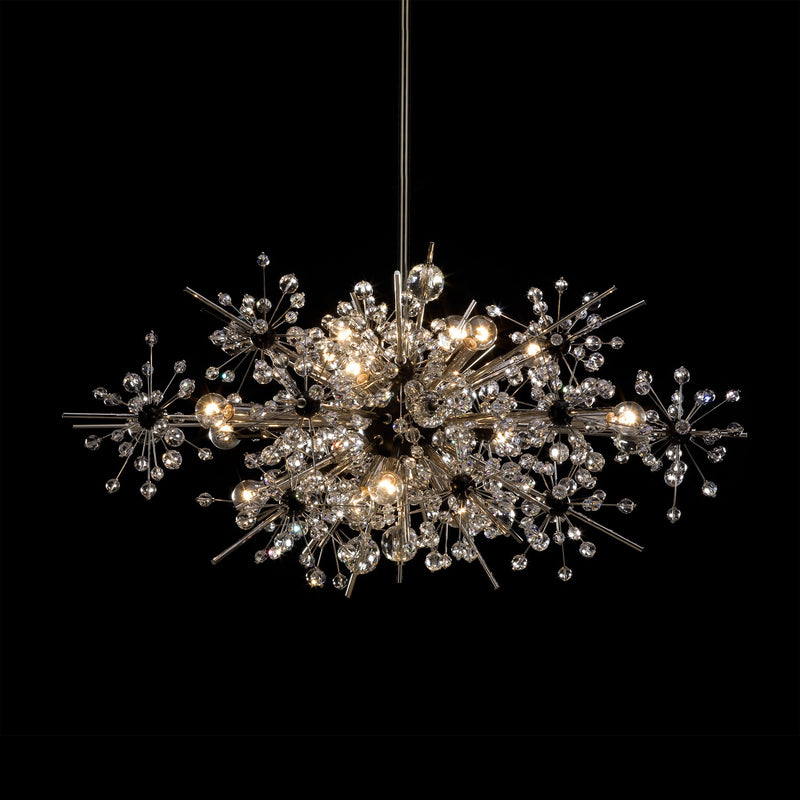 The Foyer - The Met Series by Lobmeyr is a modern chandelier with an intricate starburst design. It features numerous metallic rods and Swarovski crystal-like spheres, illuminated by several light bulbs against a black background.