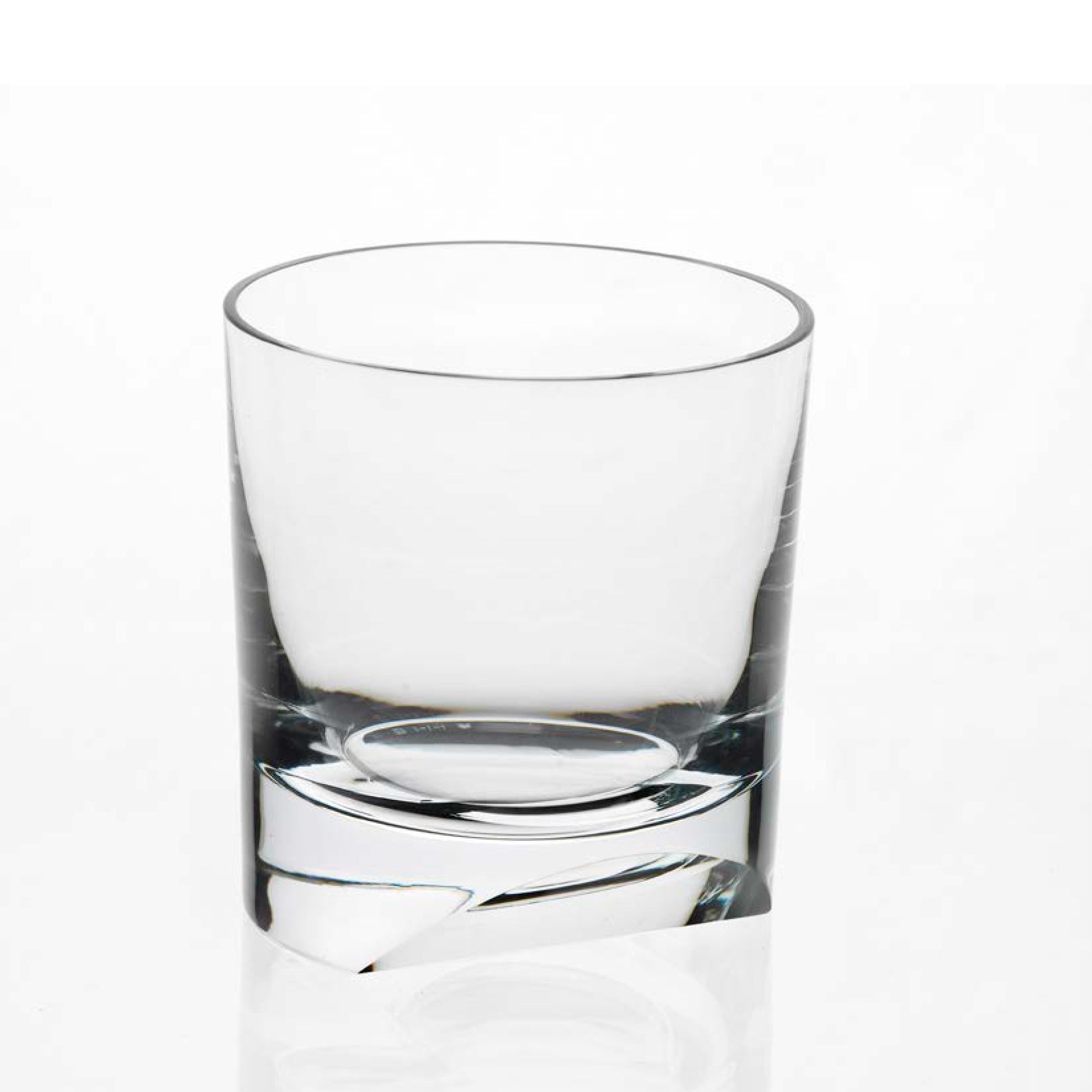 A clear, empty whiskey tumbler from Lobmeyr’s Neo Cut I Collection, featuring thick walls and a sturdy, slightly rounded base, is centered against a plain white background, capturing the refined elegance of Vienna Design Week.