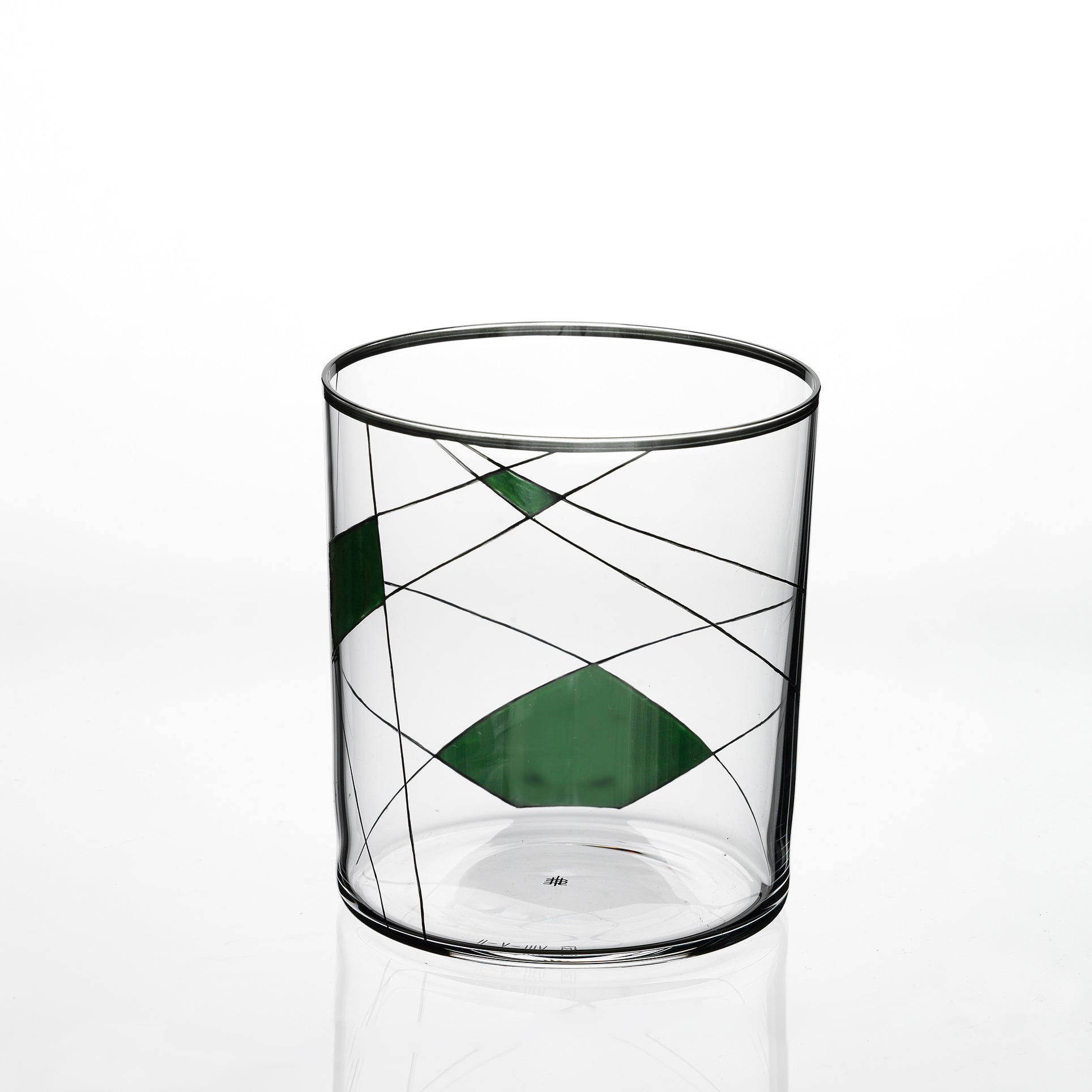 The Neo Light X by Lobmeyr is a transparent cylindrical glass with thin black lines and green geometric shapes, featuring intersecting lines that form triangular and diamond patterns, highlighting Martino Gampers innovative style.