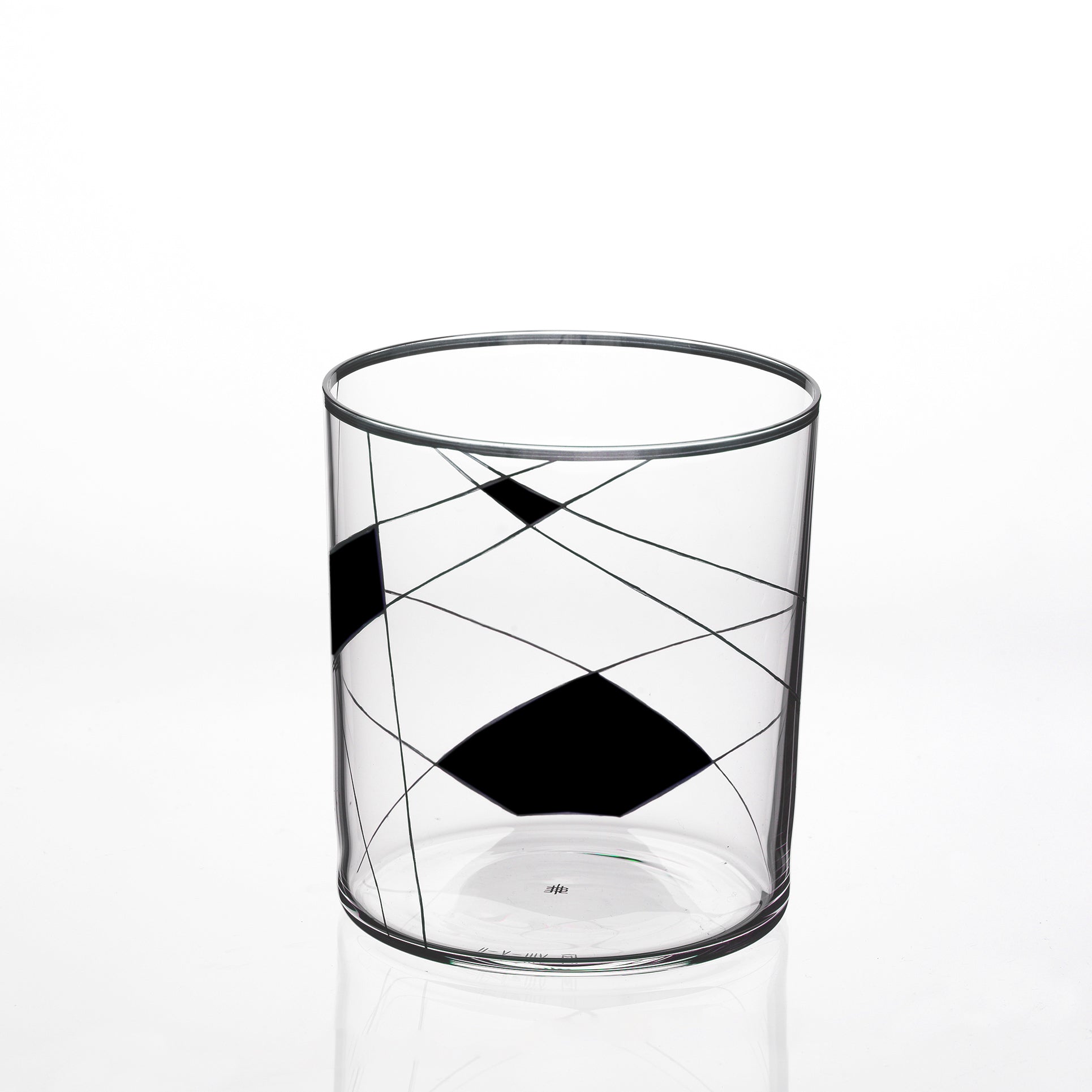 The Lobmeyr Neo Light X is a modern clear glass tumbler with black geometric shapes and intersecting lines, echoing a Martino Gamper design. Its plain white backdrop highlights the contemporary ornament pattern.