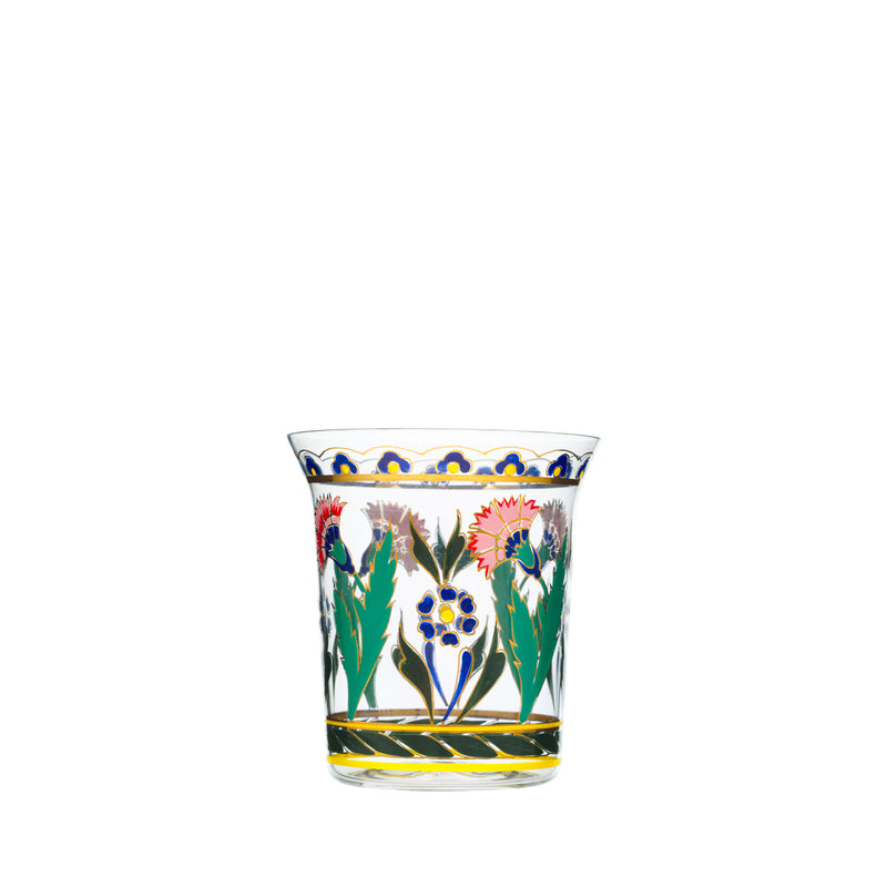 The Oriental Flower Tumbler by Lobmeyr is a clear glass adorned with colorful floral patterns of red, blue, and yellow flowers with green leaves. Intricate borders at the top and bottom add a touch of oriental ornamentation.