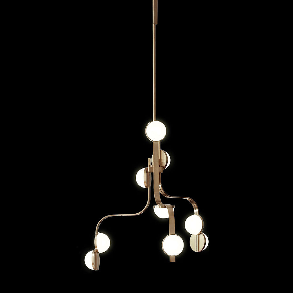 The Script Chandelier by Lobmeyr boasts a minimalist design with multiple branches, each ending in a glowing LED bulb. Suspended against a black backdrop, its elegant brass-toned metal structure echoes the Viennese Art Deco style.