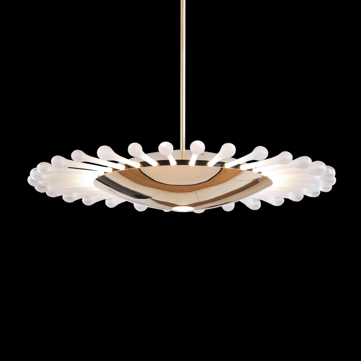 The Lobmeyr Space Ship Ellen pendant light features a central metallic reflector and a circle of white, bulbous glass elements, reminiscent of UFOs and evoking space travel, all set against a black background.