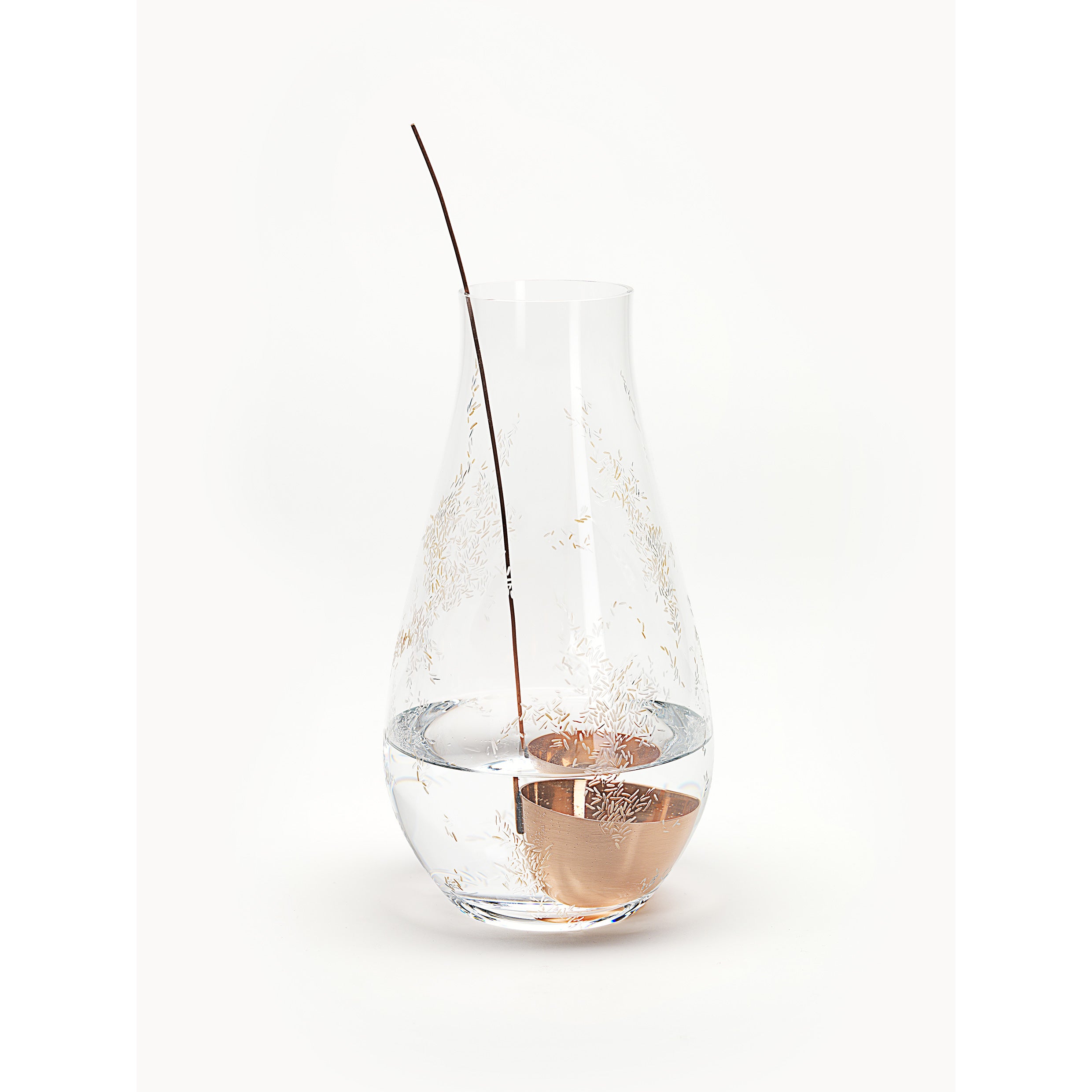 The Still Series by Lobmeyr features a clear, elegantly shaped vase with a thin branch inside, reminiscent of engraved crystal. Its water-filled minimalist design contrasts beautifully against the plain white background.