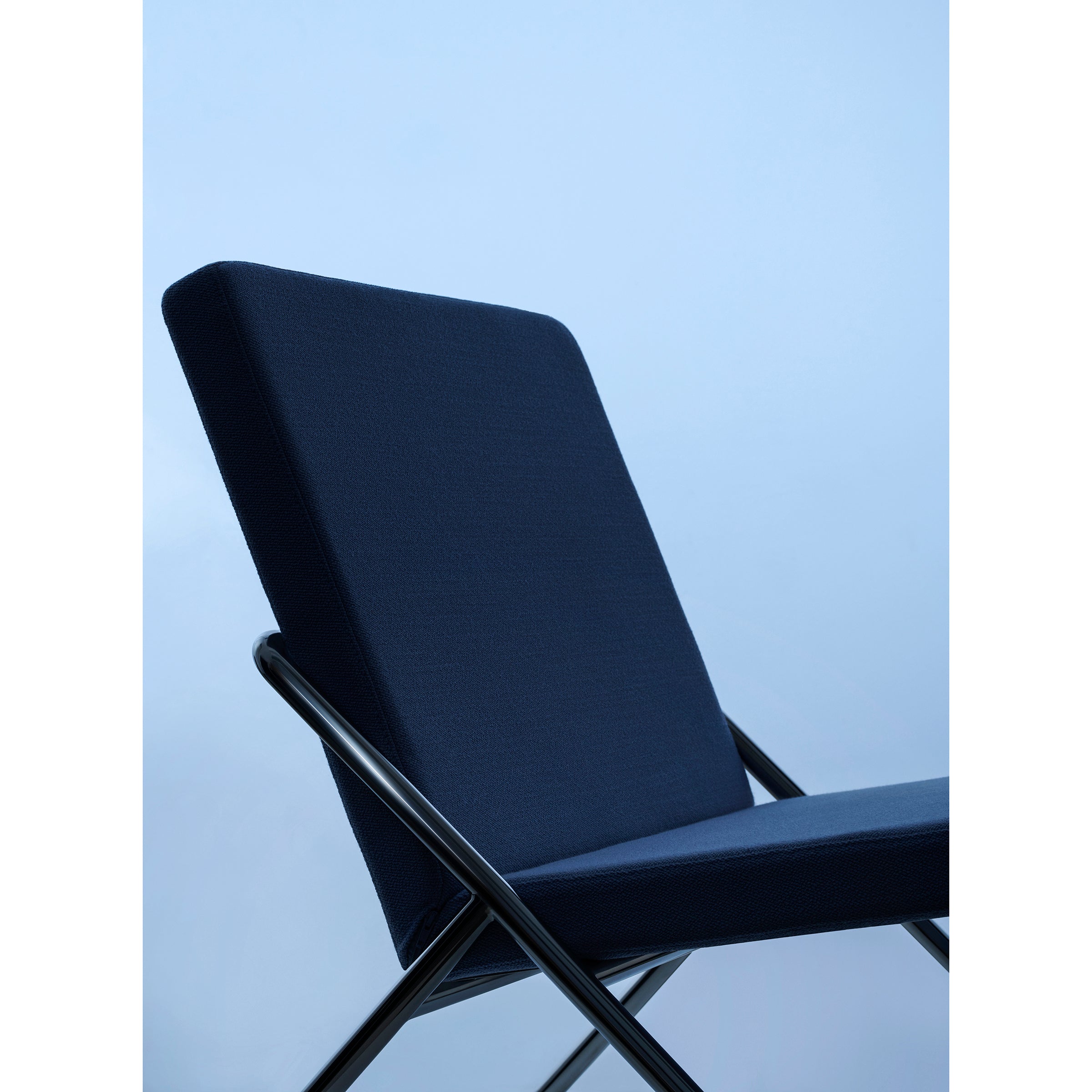 Close-up of the DL2 Euclides Two-Seater by Loehr, featuring a sleek, minimalist design. The upholstered dark blue seating is supported by a crisscross metal frame, with a light blue gradient background enhancing the calm atmosphere.
