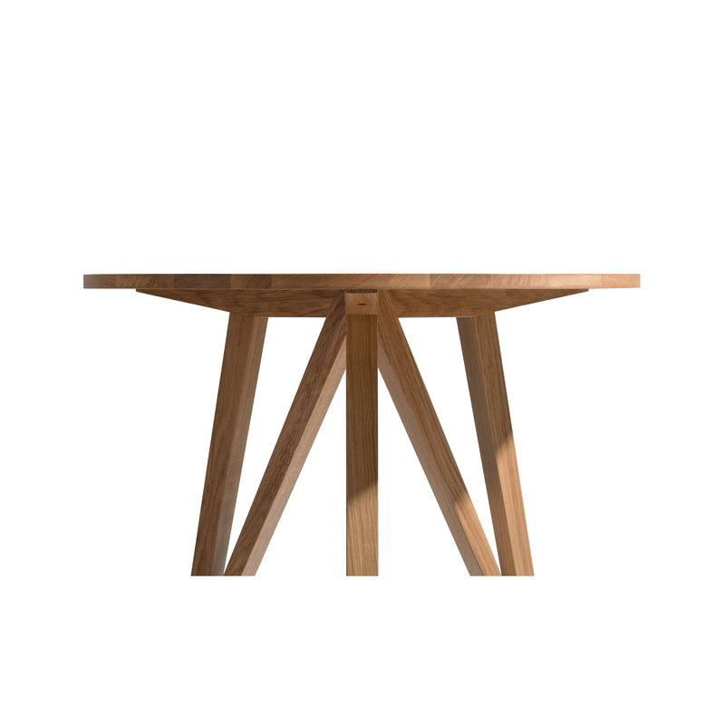 The JL3 Faber Bistro Table by Loehr is a round, minimalist wooden table with a smooth oak tabletop and geometric angled legs forming a sturdy base. Its natural finish highlights the oak grain, showcasing northern European design elegance against a white background.