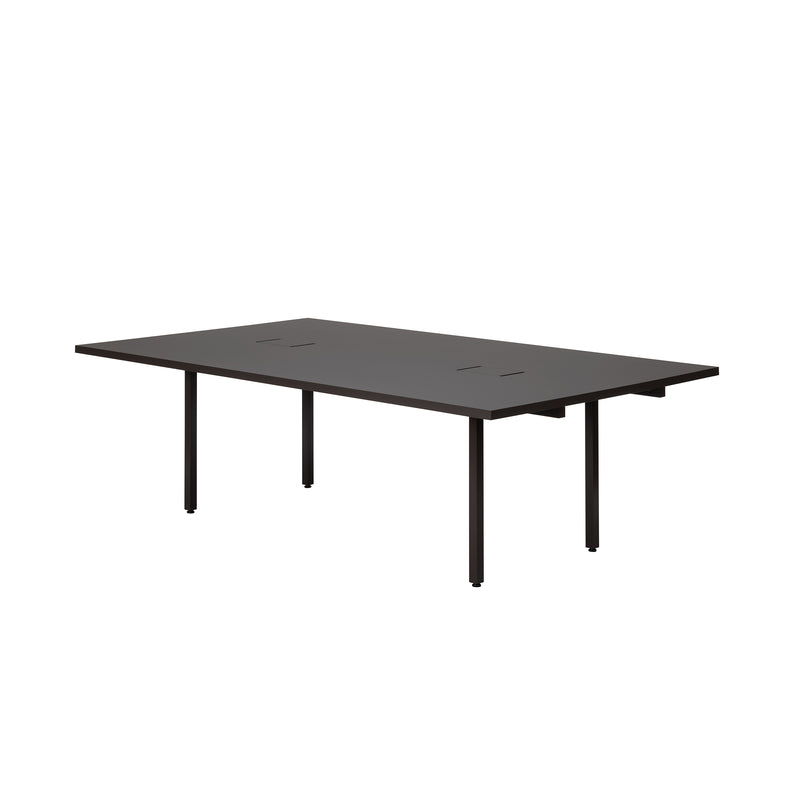 The L2 Eno Worktable by Loehr is a sleek, modern black rectangular desk with thin legs and two cut-out slits for cable management. Its minimalist design makes it ideal as both a hybrid workstation and conference room table.