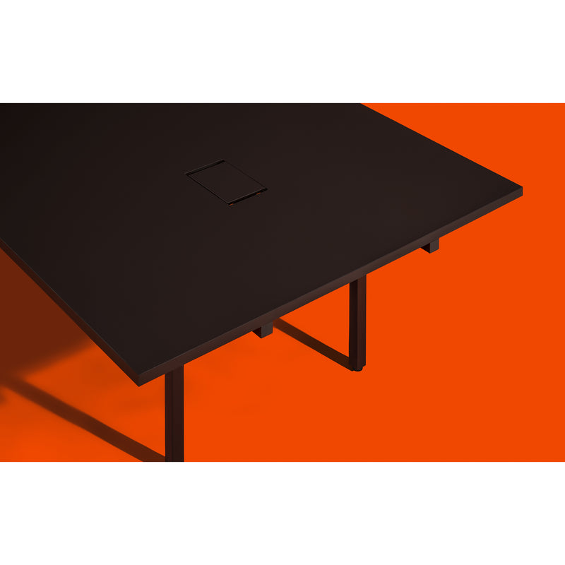 The sleek L2 Eno Worktable by Loehr stands stylishly against a vibrant orange backdrop. Its minimalist design includes a small rectangular opening for cable management, showcasing a modern, geometric aesthetic ideal for chic hybrid workstations.