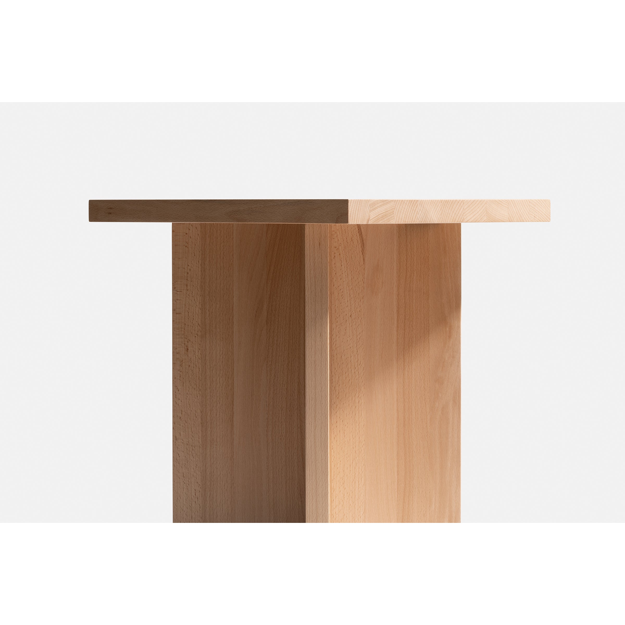 The L6 Corinth Side Table by Loehr is a minimalist piece made from solid beech, featuring a geometric design with a rectangular top and intersecting vertical beam. This sculptural wooden table looks stunning against a plain white background.