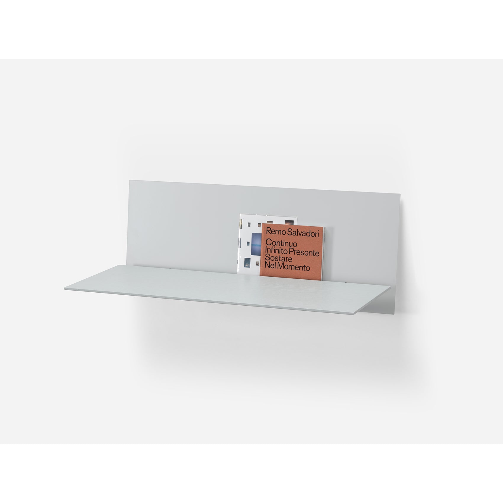 The S1 CHAPTER Bureau by Loehr is a wall-mounted, minimalist piece with a matte finish. It elegantly holds two books upright against its back panel, featuring clean lines for a functional and modern design.