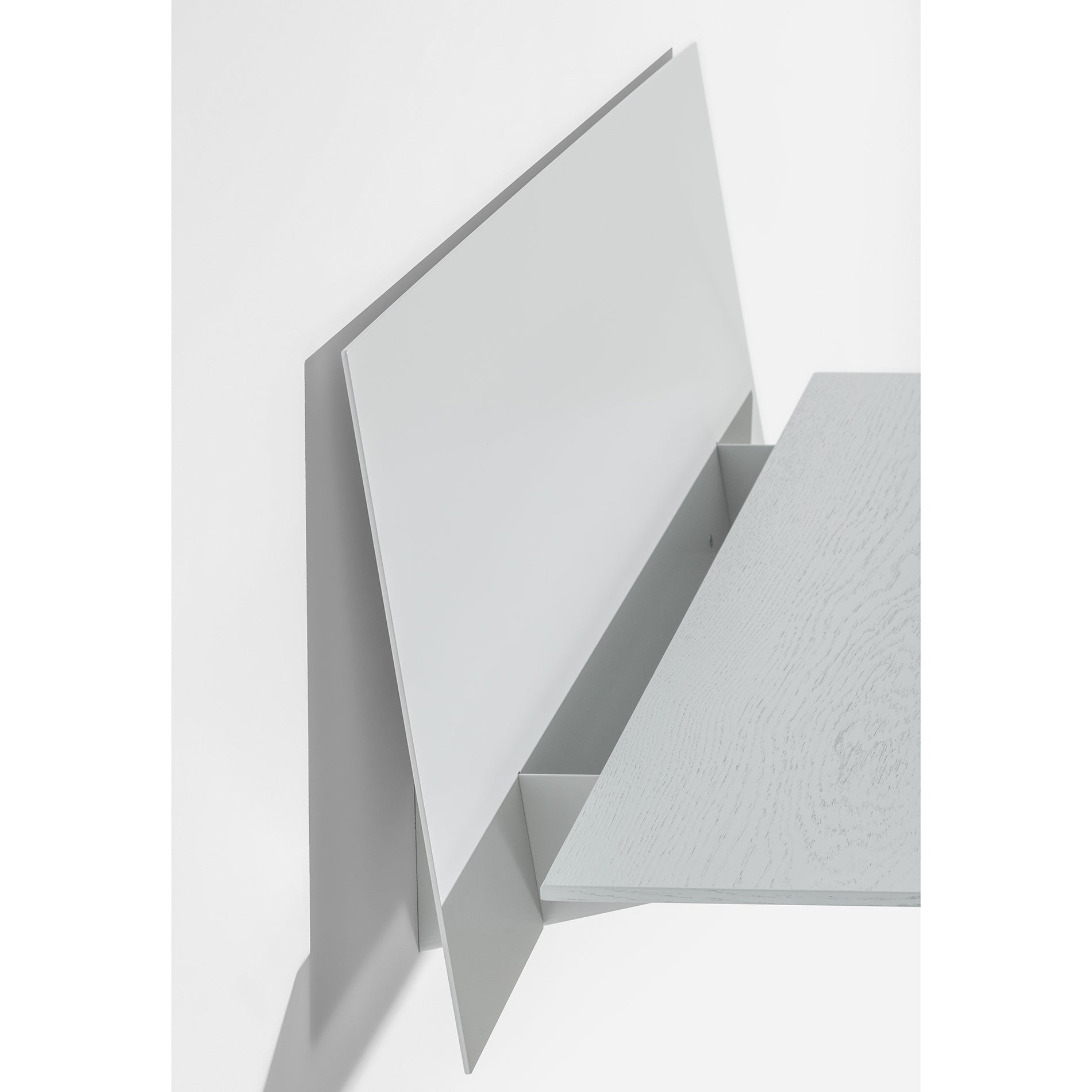 The minimalist S1 CHAPTER Bureau by Loehr features a seamless flat surface and simple back panel, perfect for a modern work environment. This wall-mounted, fold-up desk in light gray offers a sleek design set against a white background.