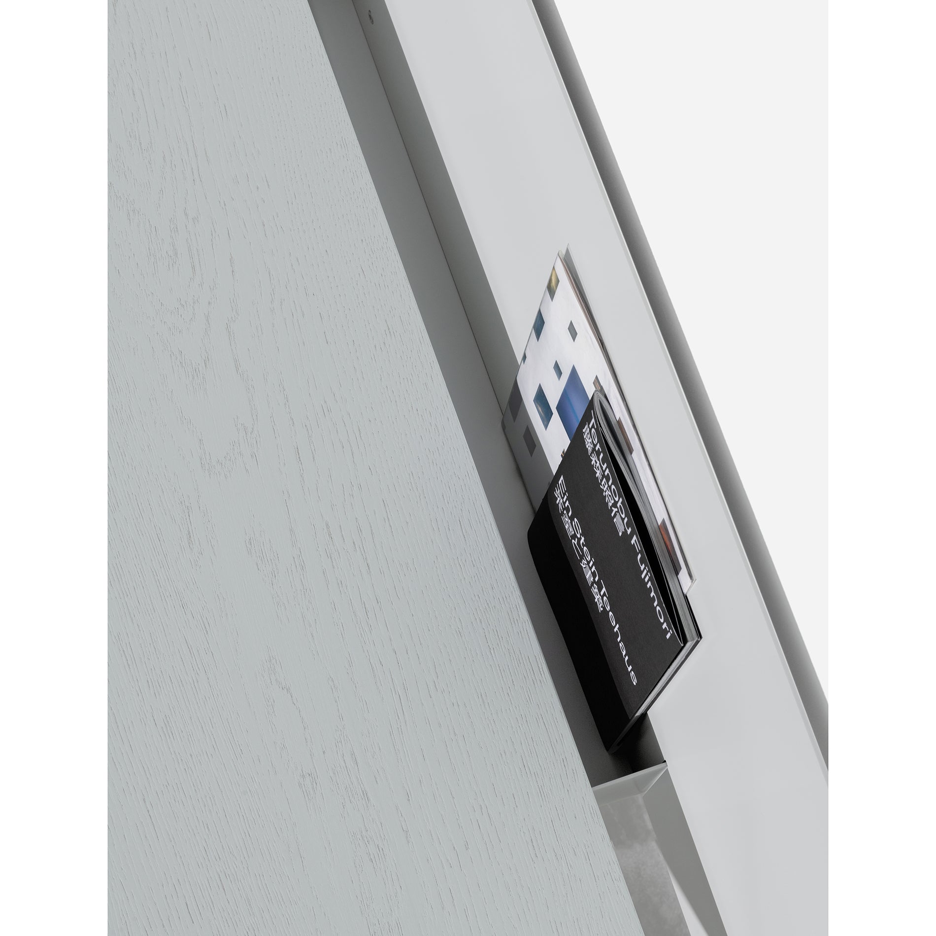 A holder with diverse brochures sits on the fold-up tabletop of the S1 CHAPTER Bureau by Loehr. The light wood background with subtle grain complements its sleek, multifunctional design.