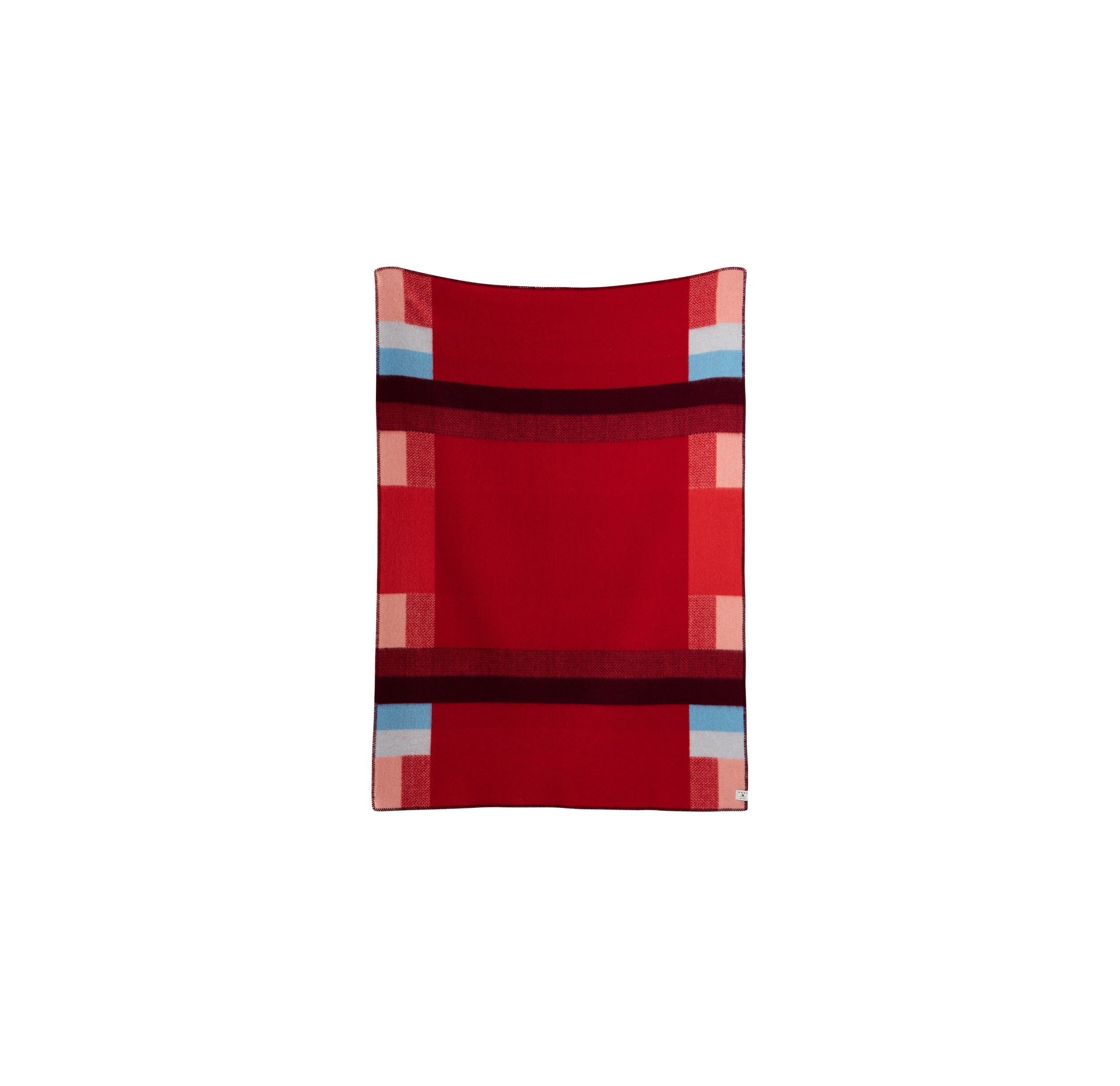 The Mikkel Large Throw by Roros is a red rectangular blanket made from soft Norwegian wool. It features Bauhaus-inspired geometric patterns in shades of pink, burgundy, and light blue with horizontal and vertical stripes forming a symmetrical block pattern.