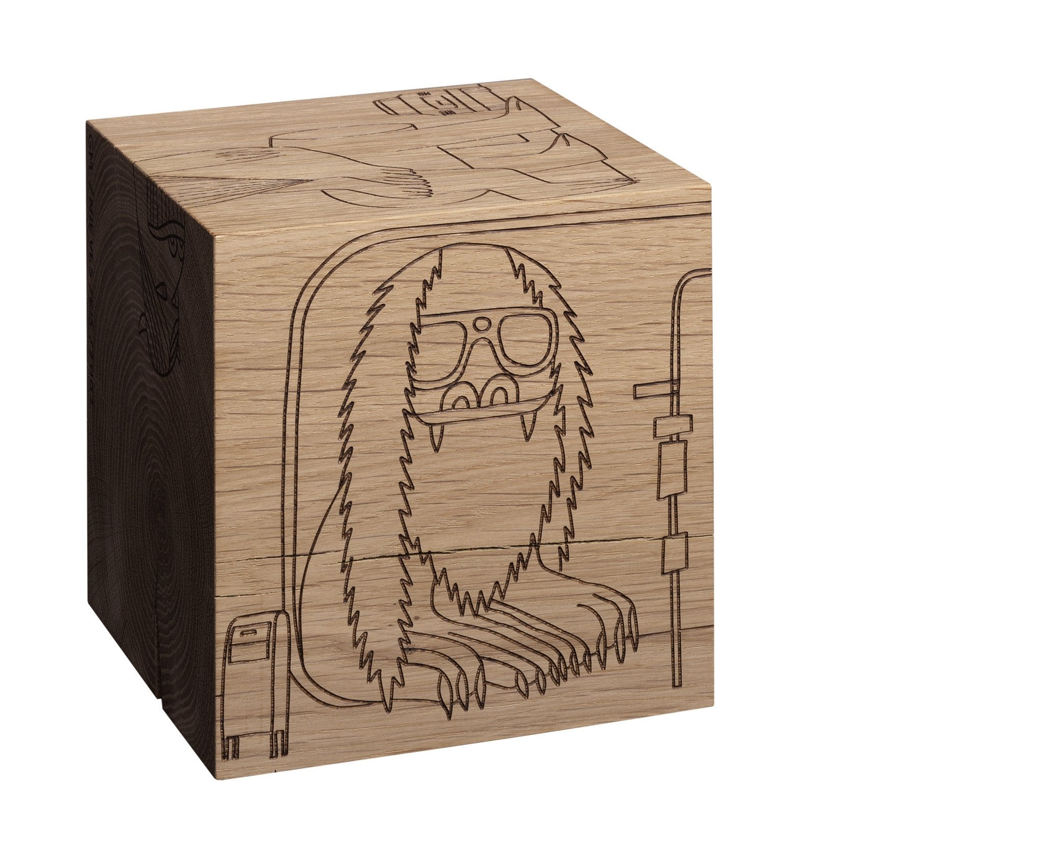 The MONSTER DICE by E15 is a wooden cube made from European oak heartwood, featuring a minimalist laser-engraved cartoon-style illustration of a furry dog with glasses and a suitcase, sitting in a subway train.