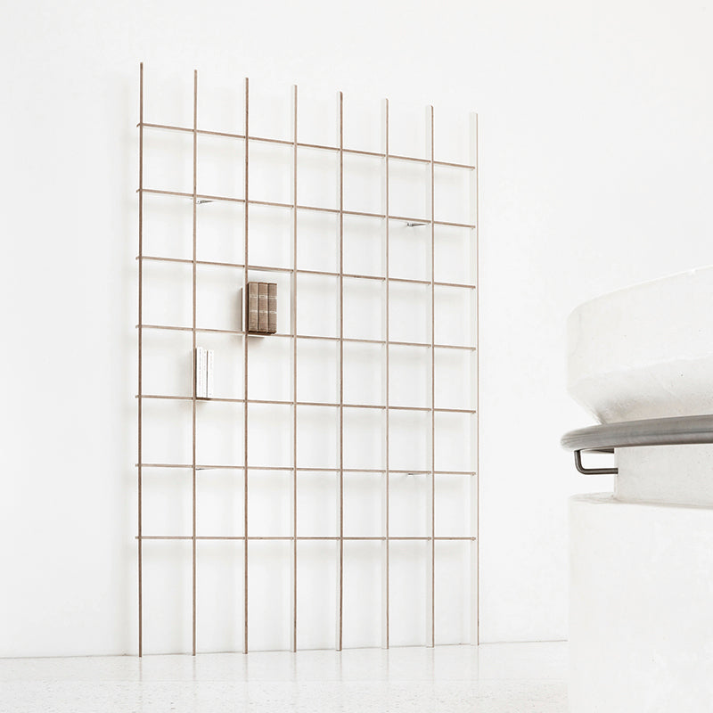A minimalist room showcases the Open bookcase by Martin Breuer Bono against a white wall with two books. A partial view of a white sculptural object complements the clean and modern aesthetic.