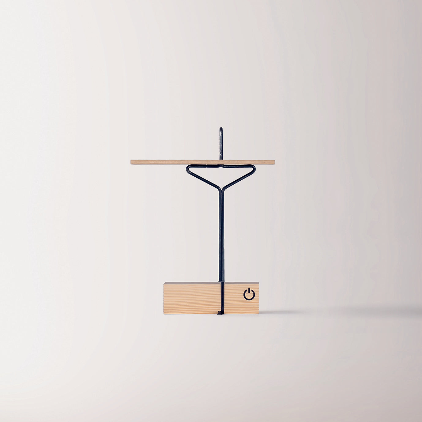 The Abgemahnt by Moormann features a minimalist design with a wooden base and slim black metal frame. A horizontal wooden shelf supports the light source, while a power symbol sits on the base. The plain background highlights the lamps modern aesthetics, echoing Nils Holger Moormanns style.