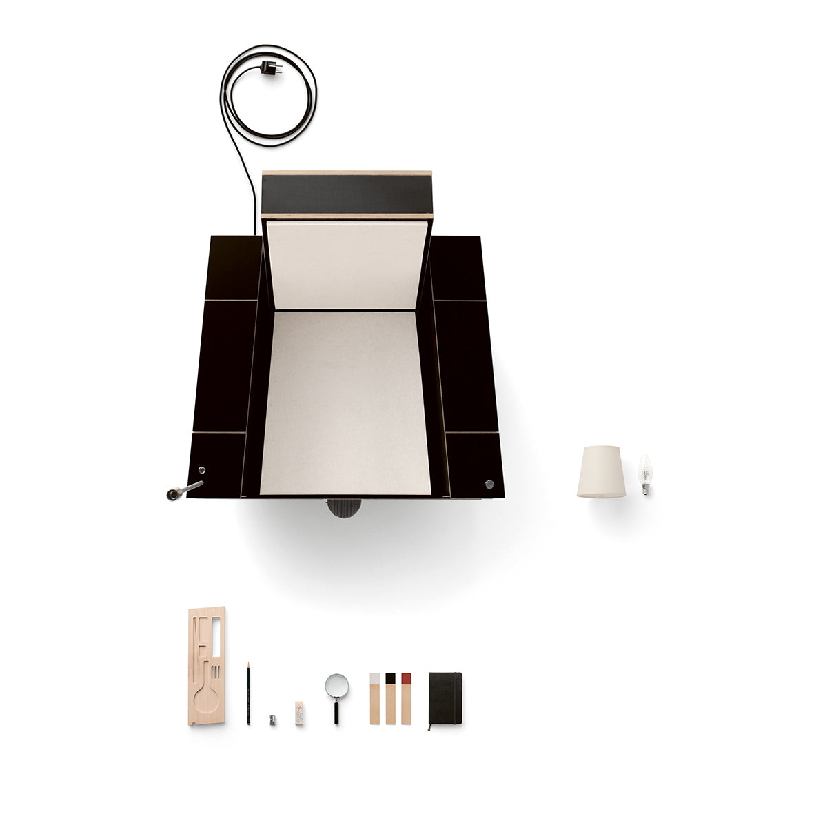 An overhead view of the Bookinist by Moormann, a black desk with a recessed center featuring a wooden tray, lamp, notebook, magnifying glass, and writing tools. Nearby is a movable chair for comfort and efficiency on the crisp white background.