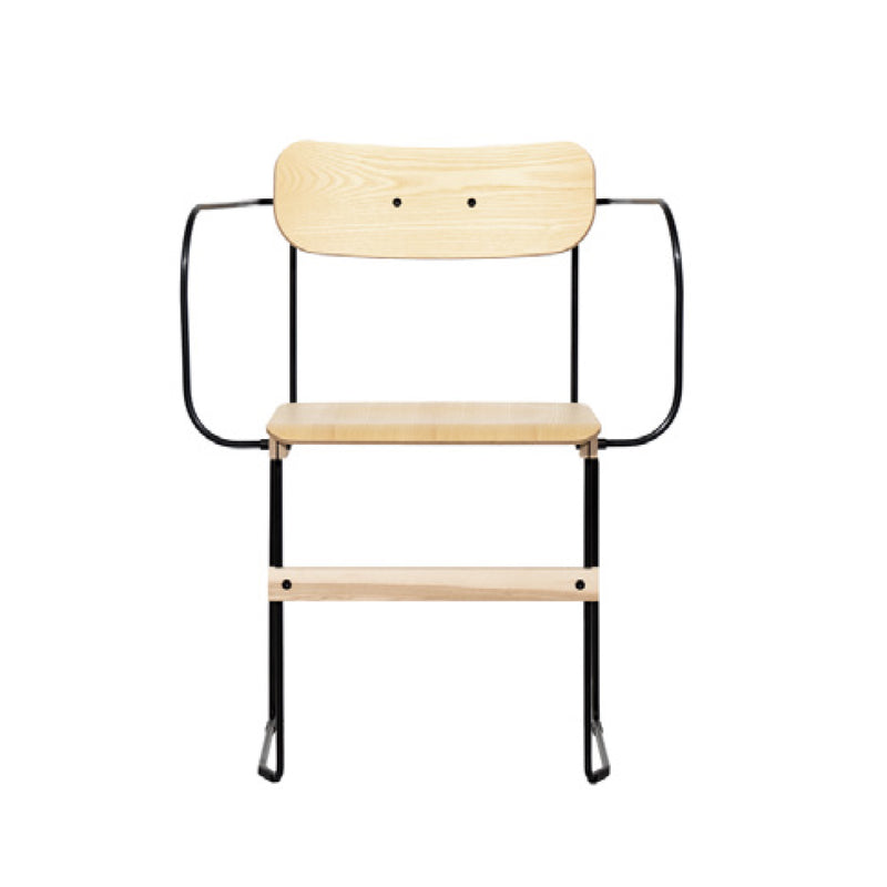 The Bruto Armchair by Moormann is a minimalist chair with a flexible design, featuring a light wood seat and backrest, black metal armrests, and a steel base frame. Its sleek structure and neutral colors enhance its contemporary aesthetic.