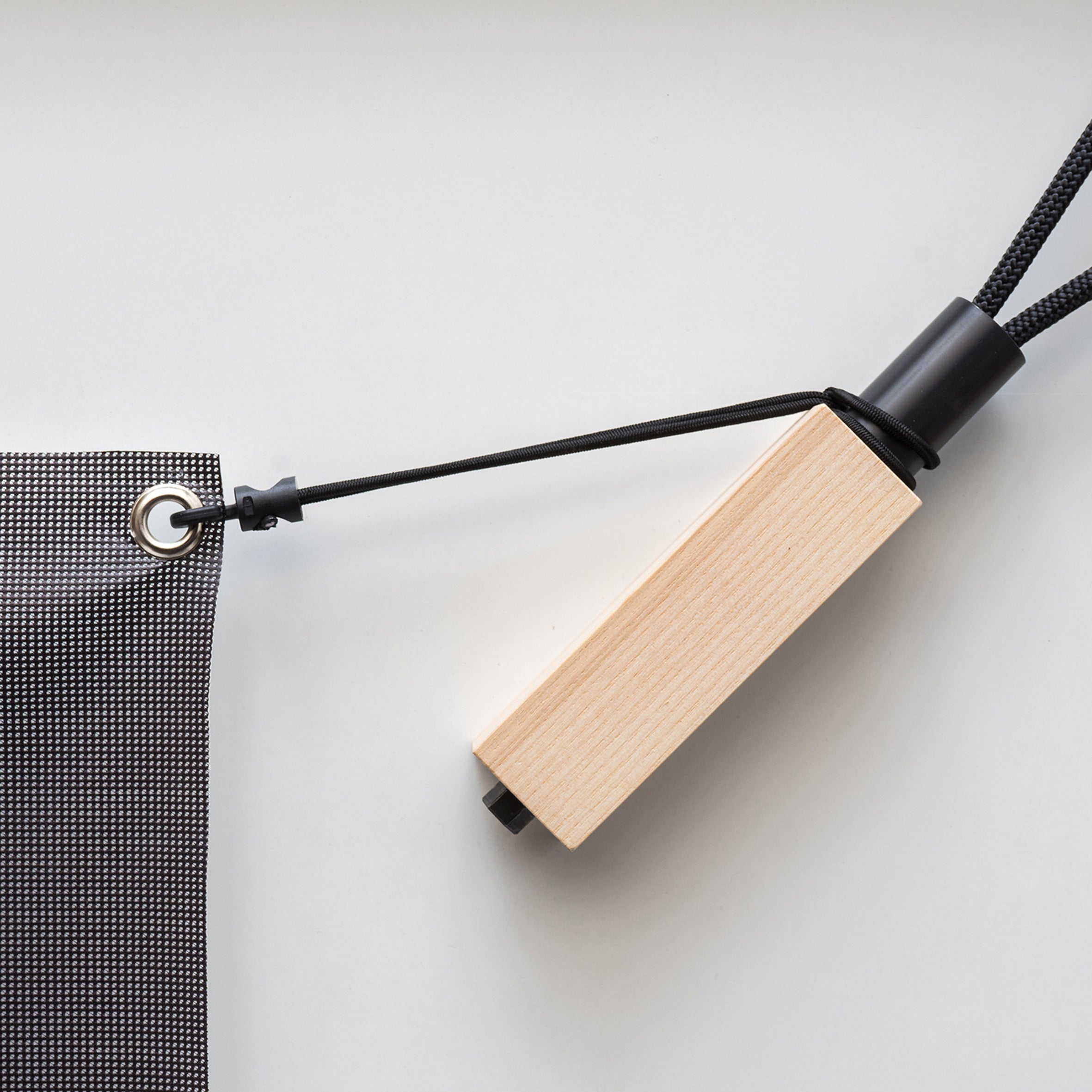 The Moormann Cable Net elegantly pairs a wooden handle with black mesh fabric, featuring a cord and metal grommet reminiscent of tensioning hooks, complemented by a sleek black neck and matching string loop, all on a white surface.