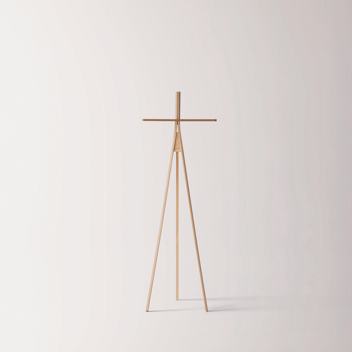 Moormanns Der Kleine Lehner is a minimalist wooden coat rack featuring a tripod base and horizontal bar, providing space-saving elegance against a plain light background.