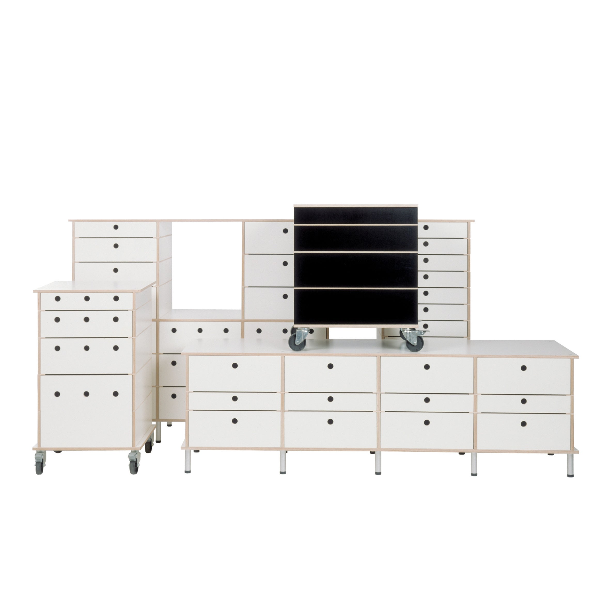 The Lader by Moormann is a modular shelving unit crafted from birch plywood. It features customizable options, including white units with black circular handles, some on wheels, and one with black drawers. The setup forms an asymmetrical shape against a white background.