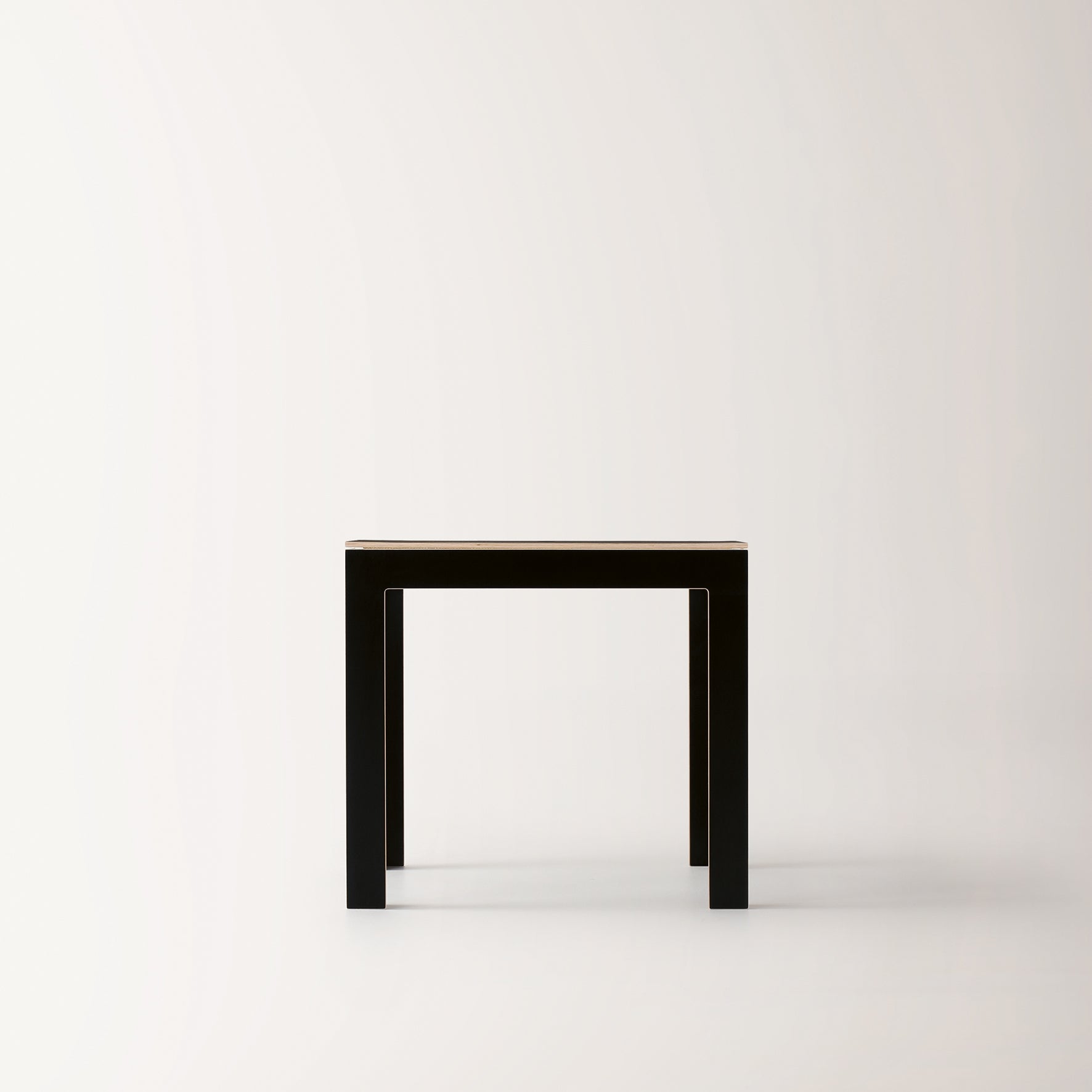 The Last Minute by Moormann is a minimalist black square table made from birch plywood, featuring clean lines. Positioned against a plain white background, this space-saving piece effortlessly blends form and function.