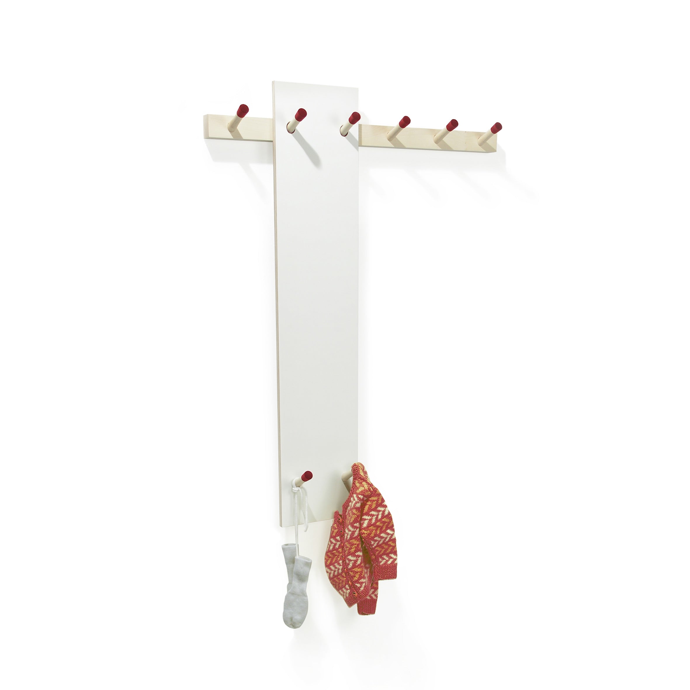 The Rechenbeispiel by Moormann is a wall-mounted coat rack with a tall white panel and red-tipped wooden hooks. A gray sock and a red patterned knit sweater hang on separate hooks, with additional horizontal hooks above for flexible storage.