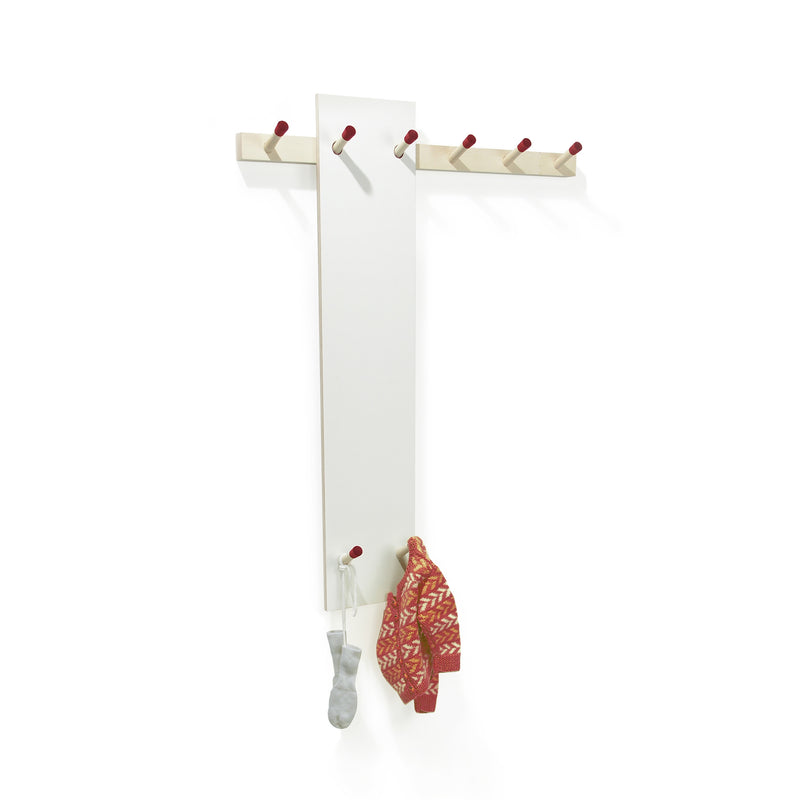 The Rechenbeispiel by Moormann is a wall-mounted coat rack with a tall white panel and red-tipped wooden hooks. A gray sock and a red patterned knit sweater hang on separate hooks, with additional horizontal hooks above for flexible storage.
