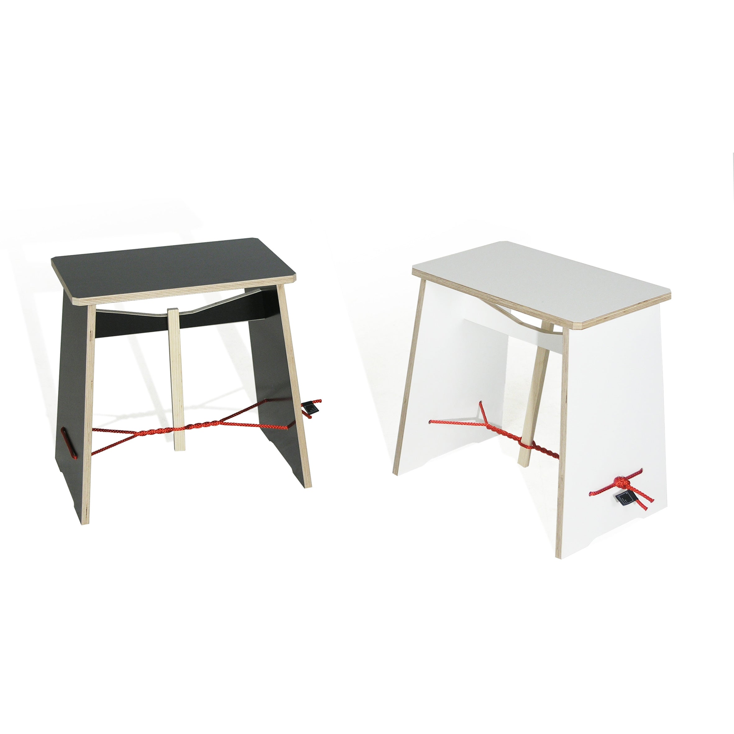 The Strammer Max stools by Moormann feature a minimalist design with black and white tabletops, wooden legs, and a red cord detail for support. These modern pieces creatively showcase simple lines and plywood panels to enhance their contrasting colors.