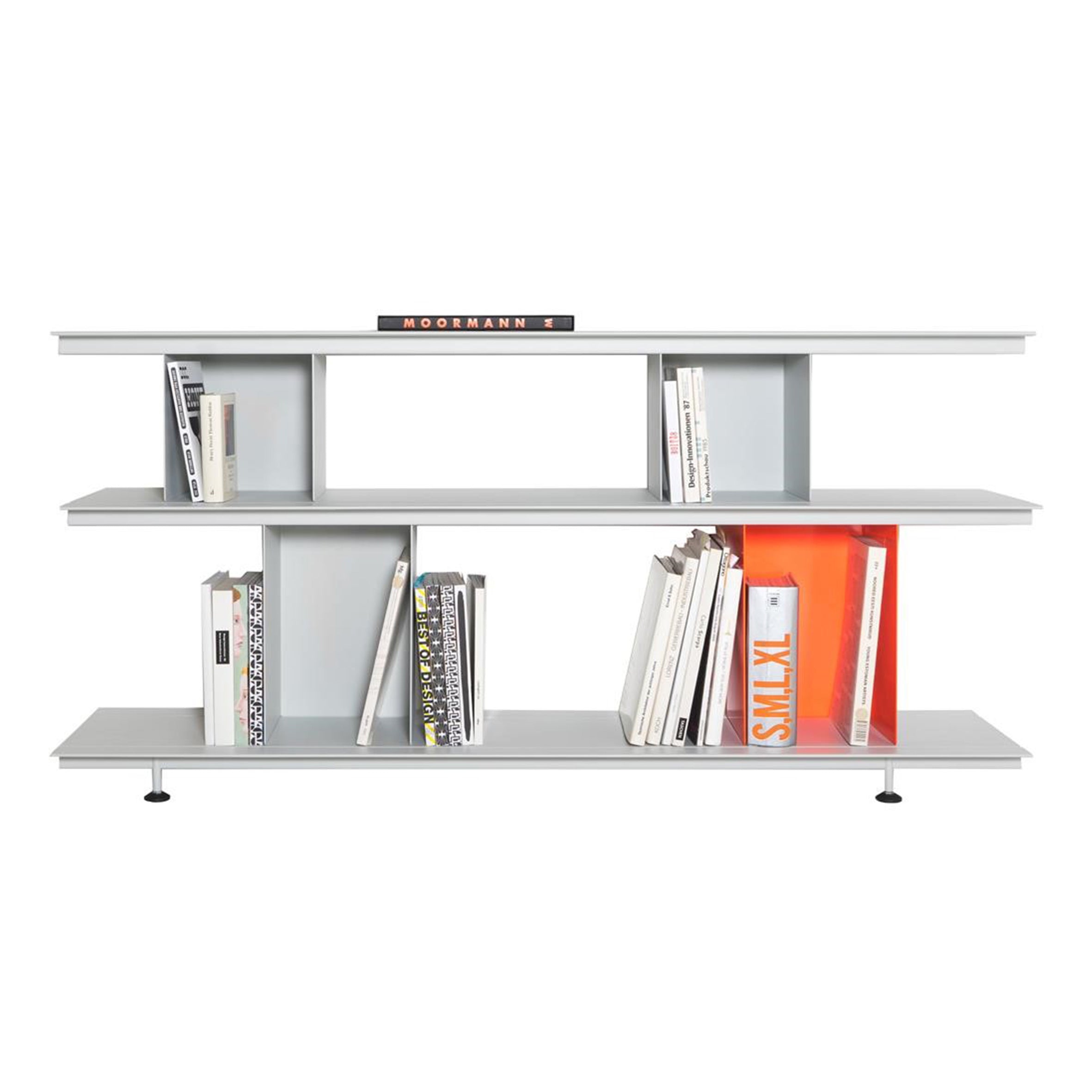 The Zoll D by Moormann is a modern, minimalist bookshelf with two levels for vertical and horizontal book placement, featuring tool-free assembly. It includes colorful spines and an orange accent panel, all in a sleek gray finish with small black feet.