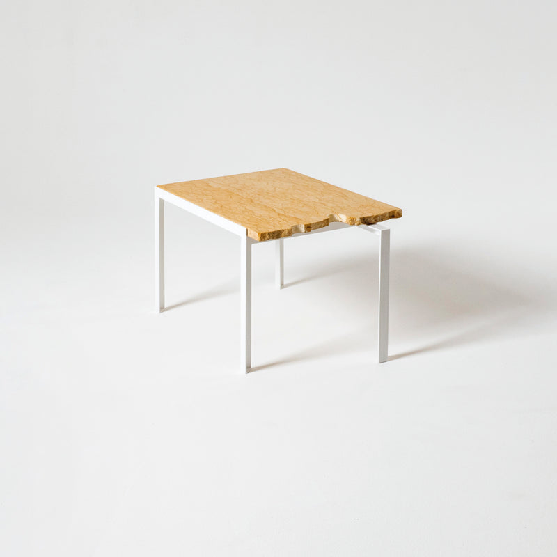 The Petite Table DAngle by Atelier Haussmann features a wooden top with a natural finish and slightly irregular edge, complemented by sleek white metal legs, all set against a plain white background.