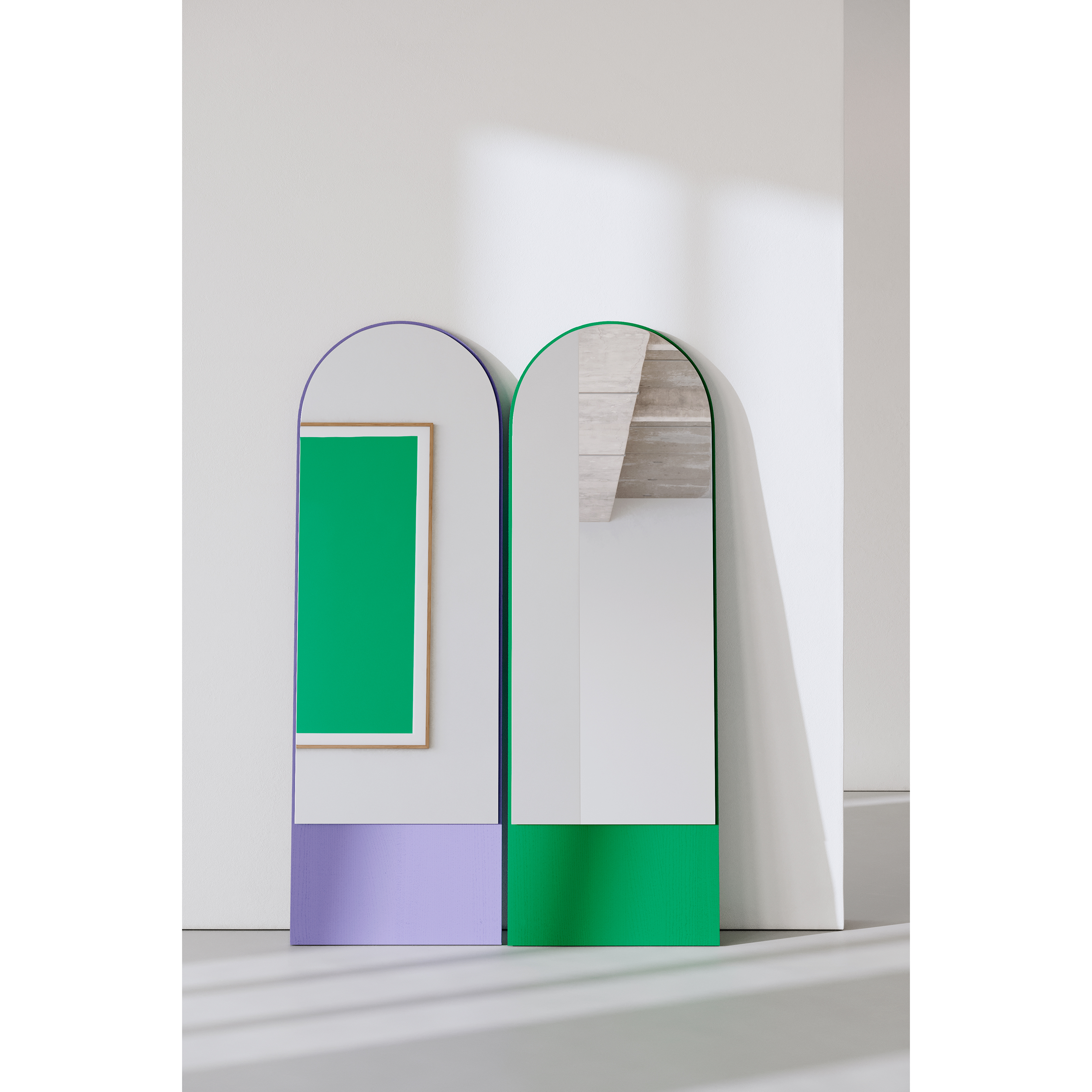 Two tall, modern FRIEDRICH 21 mirrors by Objekte unserer Tage with purple and green lacquered ash wood frames stand against a white wall. The green-framed mirror reflects the textured ceiling, and a rectangular green artwork is mounted beside them.