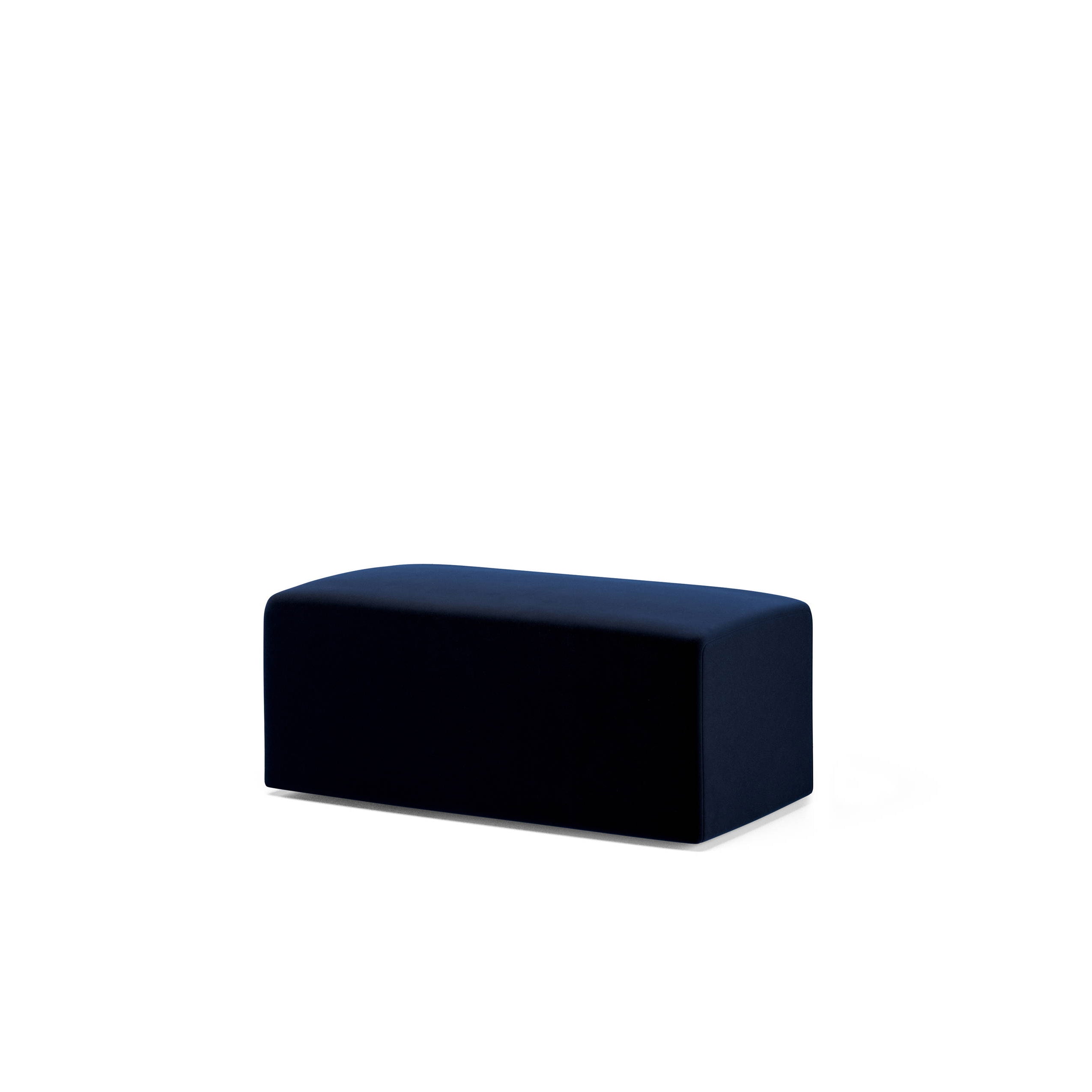 The Weber Pouf by Objekte unserer Tage, a dark rectangular ottoman with a smooth surface against a white background, complements the geometric shapes of the space.