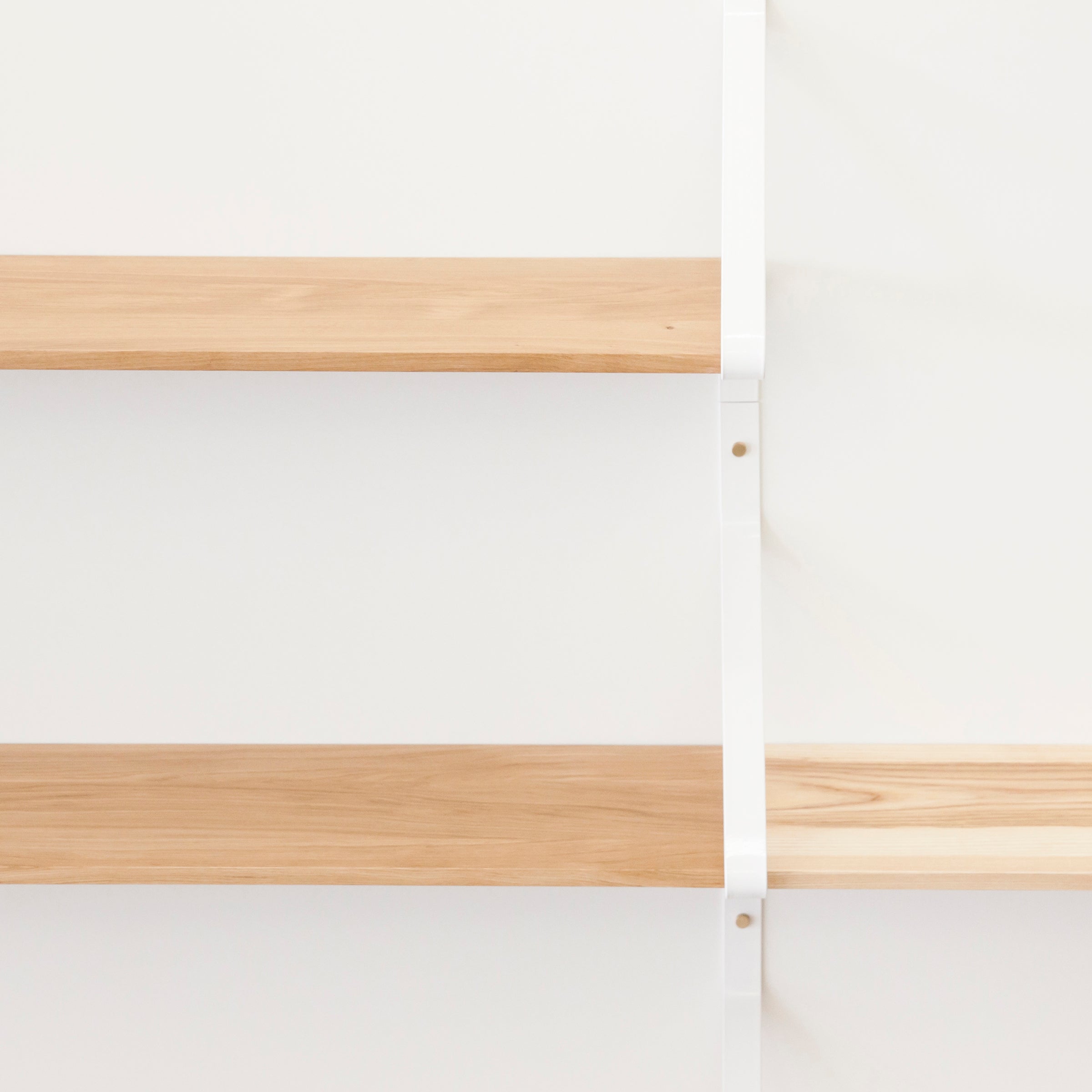 Two light brown Ribbon Shelves by One For Hundred are mounted on a white wall with powder-coated steel brackets, highlighting their minimalistic and clean design.