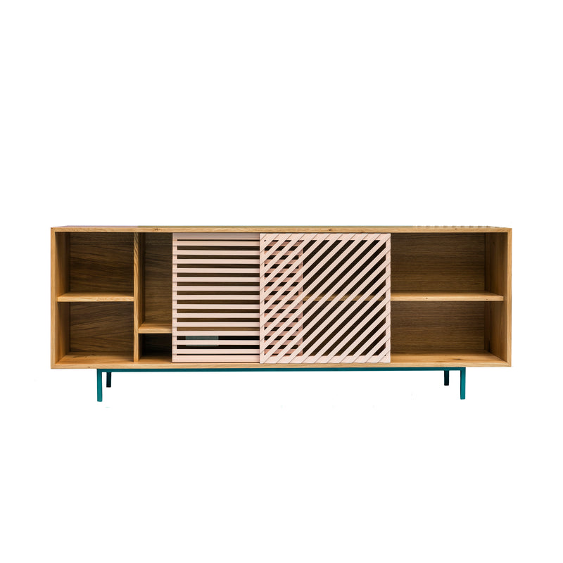 The Shadow Sideboard by One For Hundred boasts a modern design with sliding doors featuring open shelves and two diagonal striped doors in white and pink. It stands on slender teal legs, combining contemporary style and functionality in a solid wood unit.
