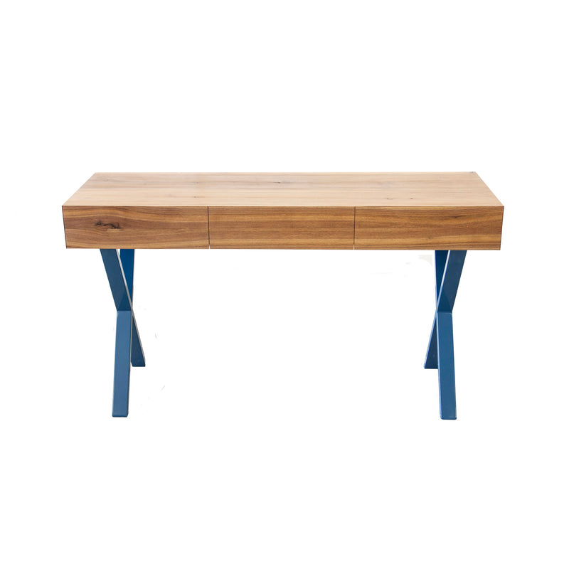 The Bar X Console by One For Hundred features a light brown solid wood top with natural grain, three drawers, and blue metal legs in an X-shape, all set against a plain white background.