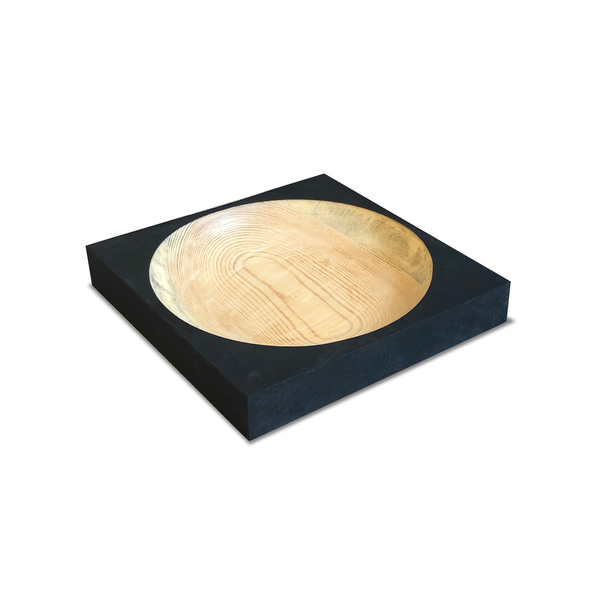 The Cavetto by One For Hundred is a modern pinewood dish with a light grain in a matte black square block. Its smooth, rounded interior contrasts the blocks edges, creating a minimalist table accessory.