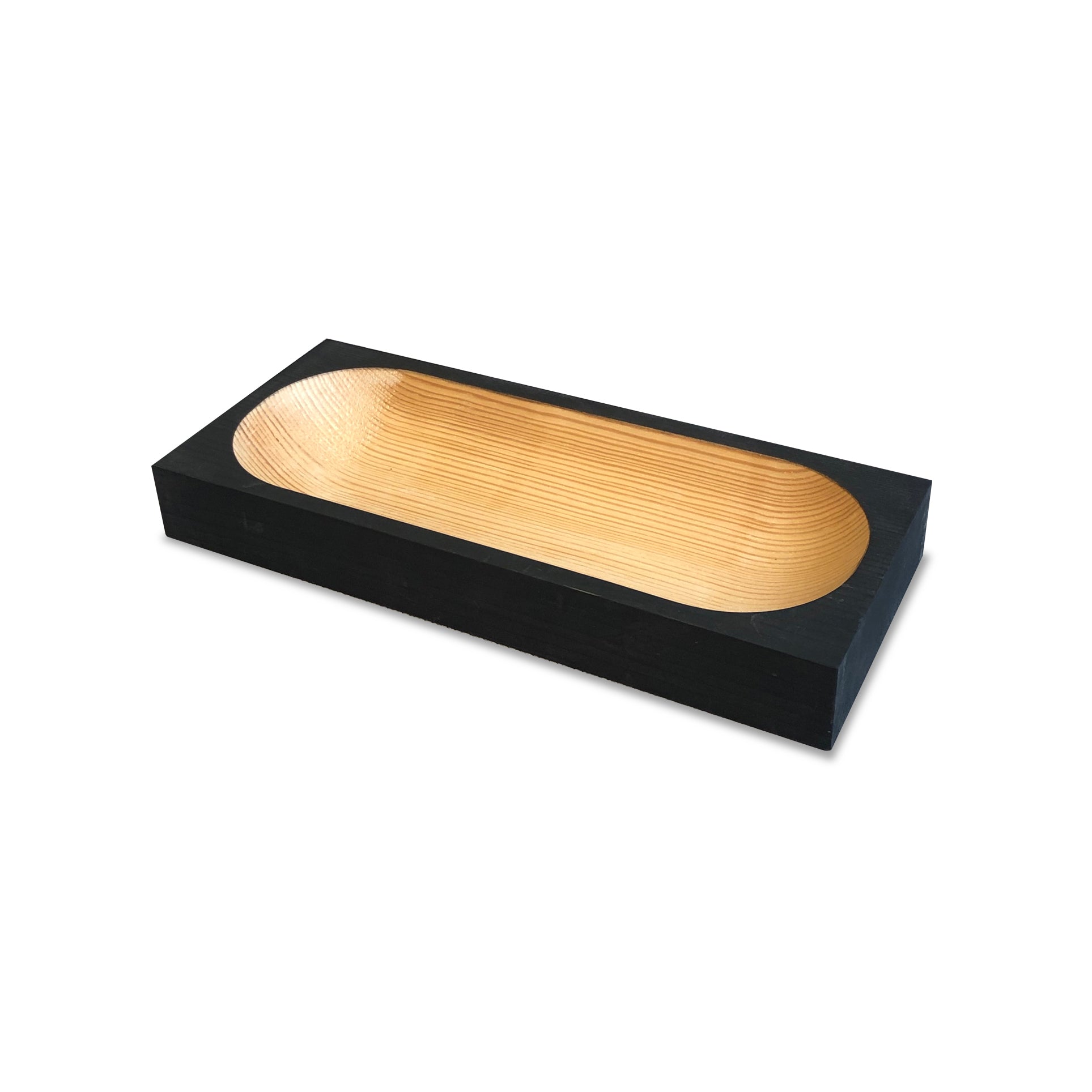 The Cavetto, a rectangular bowl by One For Hundred, combines a dark exterior with a lighter pinewood interior carved in a smooth, shallow style reminiscent of cavetto molding. Perfect for serving or decor, it adds charm to your table accessories collection against its white background.