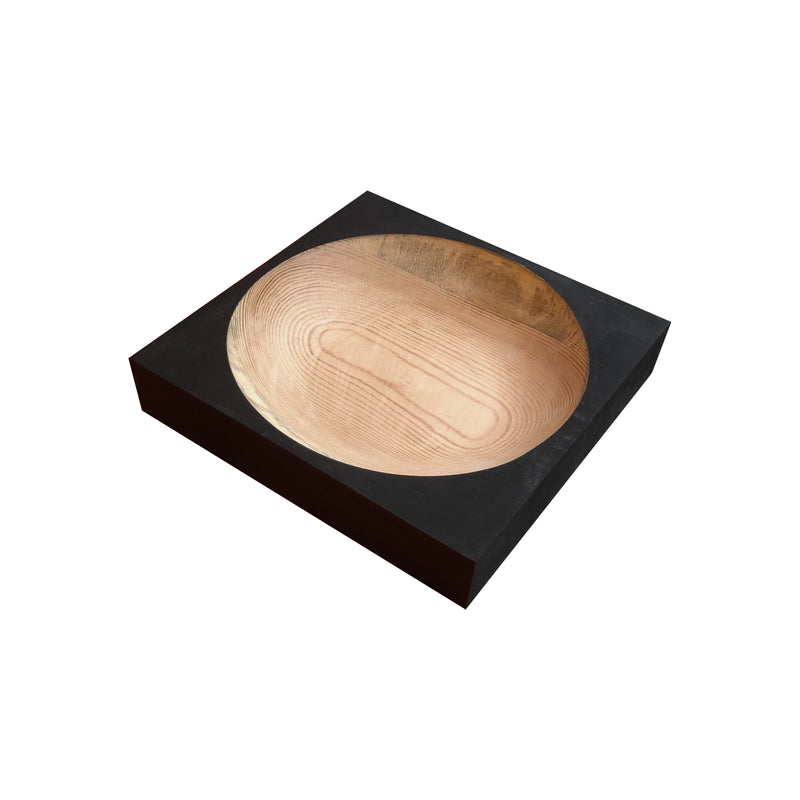 The Cavetto bowl by One For Hundred is a square wooden piece crafted from pinewood. It features natural grain patterns on a black background with concentric rings inside and a polished finish, contrasting its matte, darker exterior—an elegant addition to any table accessory collection.