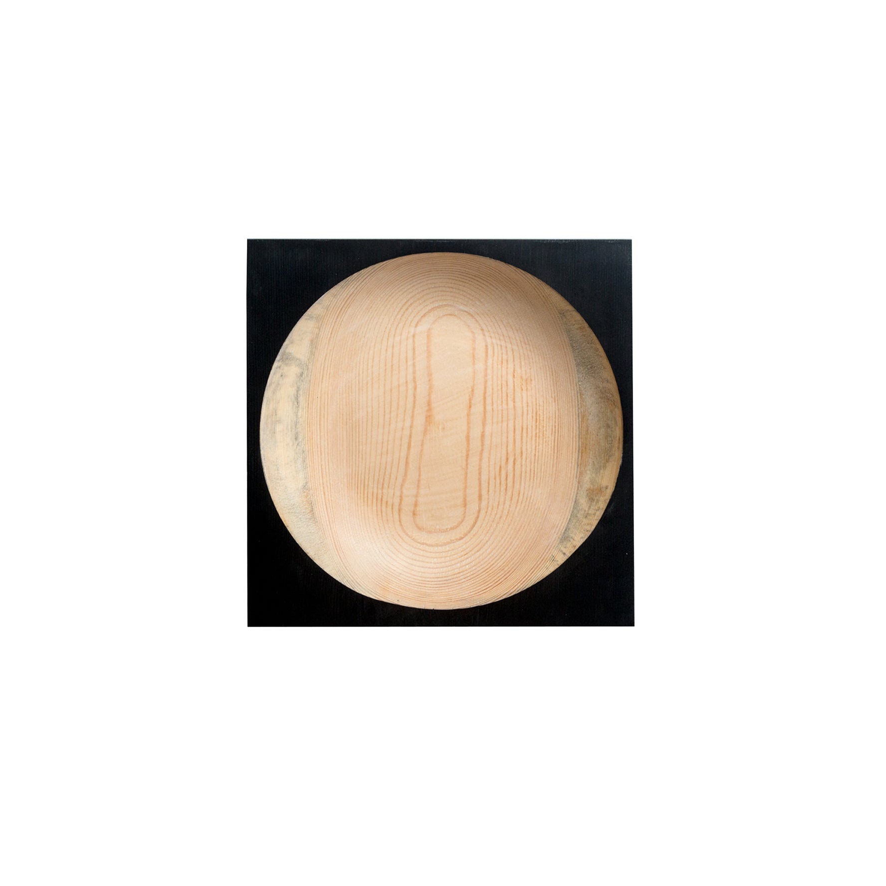 The Cavetto by One For Hundred stands out as a distinctive table accessory. This round pinewood bowl, set against a black background, showcases its smooth natural grain and light wood tone with textured cavetto edges.