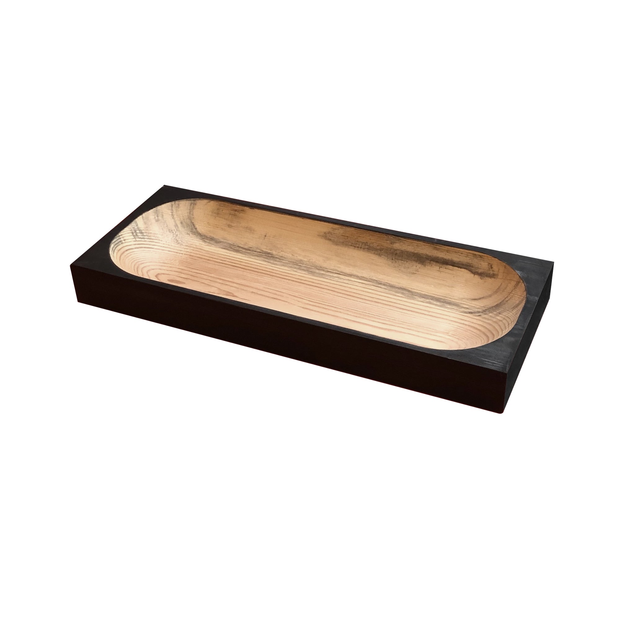 The Cavetto by One For Hundred is a rectangular tray crafted from pinewood, showcasing a dark exterior and lighter wood grain interior. With a smooth oval center depression, this elegant piece is highlighted against a plain white background.