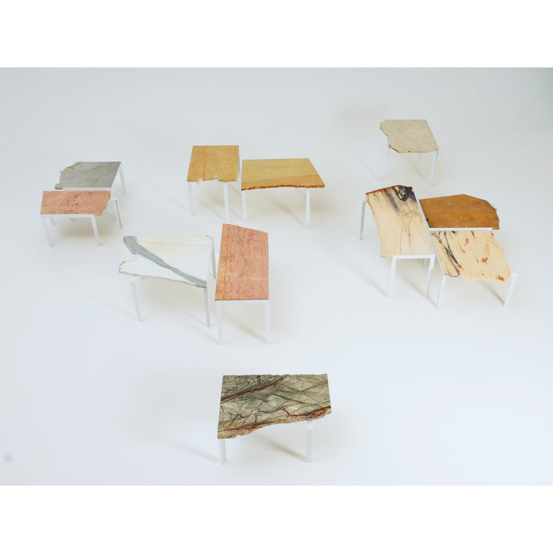 A collection of nine Petite Table DAngle by Atelier Haussmann, each with white legs and distinctively shaped and colored marble tops from remnant slabs, showcased on a plain white background.