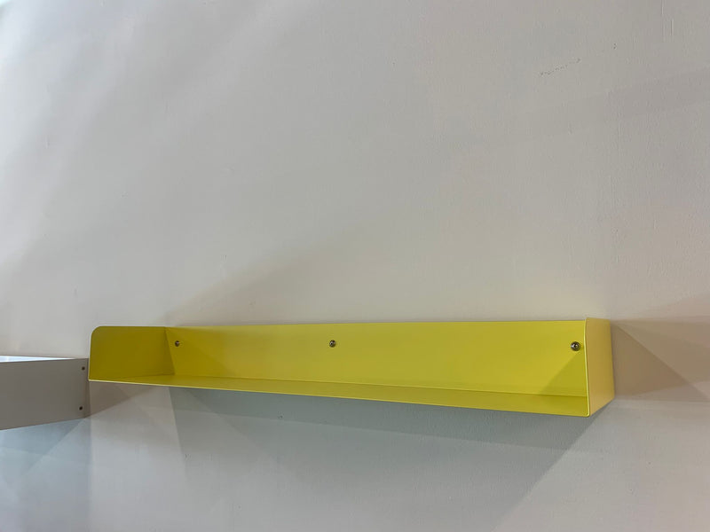 A sulfur yellow Poggibonsi Shelf by Atelier Haussmann is mounted on a white wall, casting a faint shadow to the right. Its minimalist design combines elegance and simplicity.